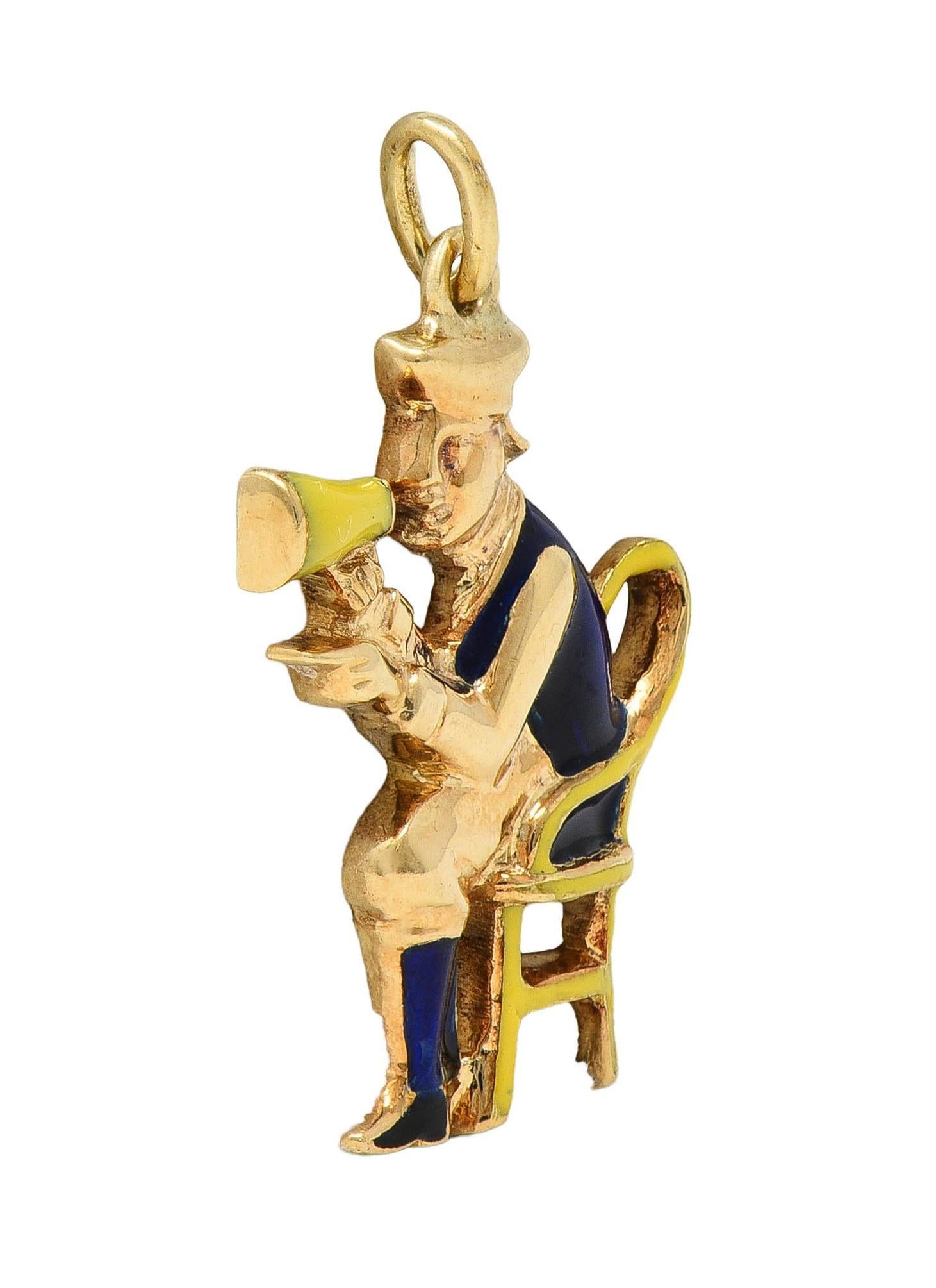 Disegnato come un uomo molto rappresentato seduto su una sedia con cappello e megafono.
Vestiti, sedia e megafono smaltati in blu cobalto e giallo
Opaco e senza perdite
Sospeso da una balla di anelli di salto
Con finitura lucida
Timbrato per l'oro a