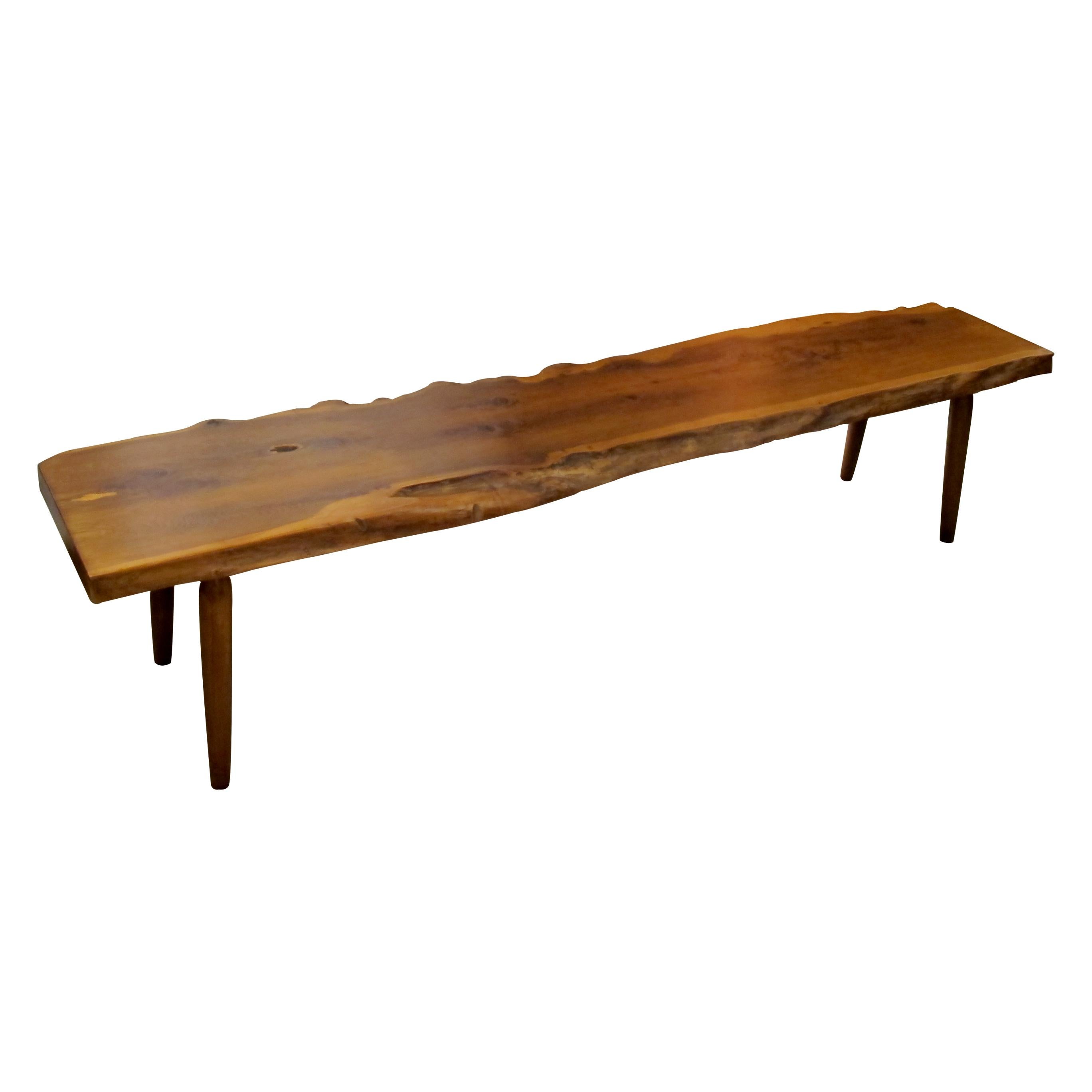 Reminiscent of some of George Nakashima's work this bench is attributed to Reynolds of Ludlow. Crafted with precision and care, the bench boasts a beautiful live edge design, showcasing the natural contours and imperfections and rich hues of the yew