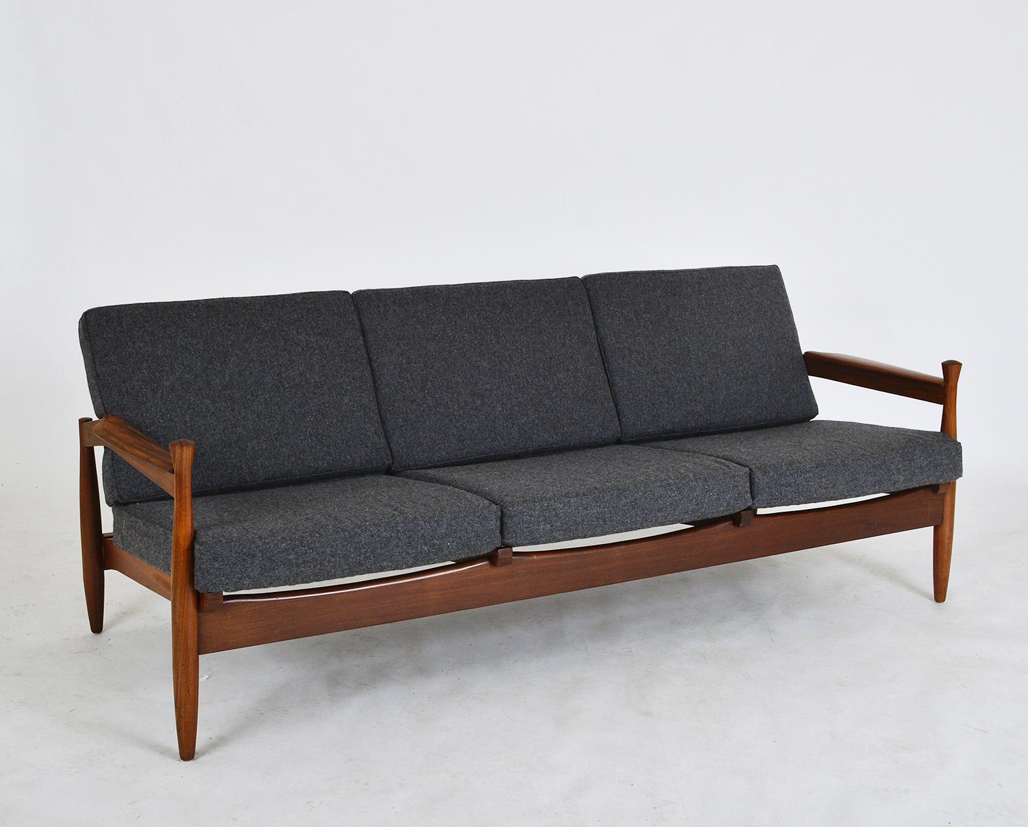 A very stylish solid African teak (Afrormosia) three-seat sofa dating from the 1960s. Designer and manufacturer unknown, although it’s very similar to pieces from the workshops of Guy Rogers. Tapered bowling-pin legs, wonderfully curved backrest,