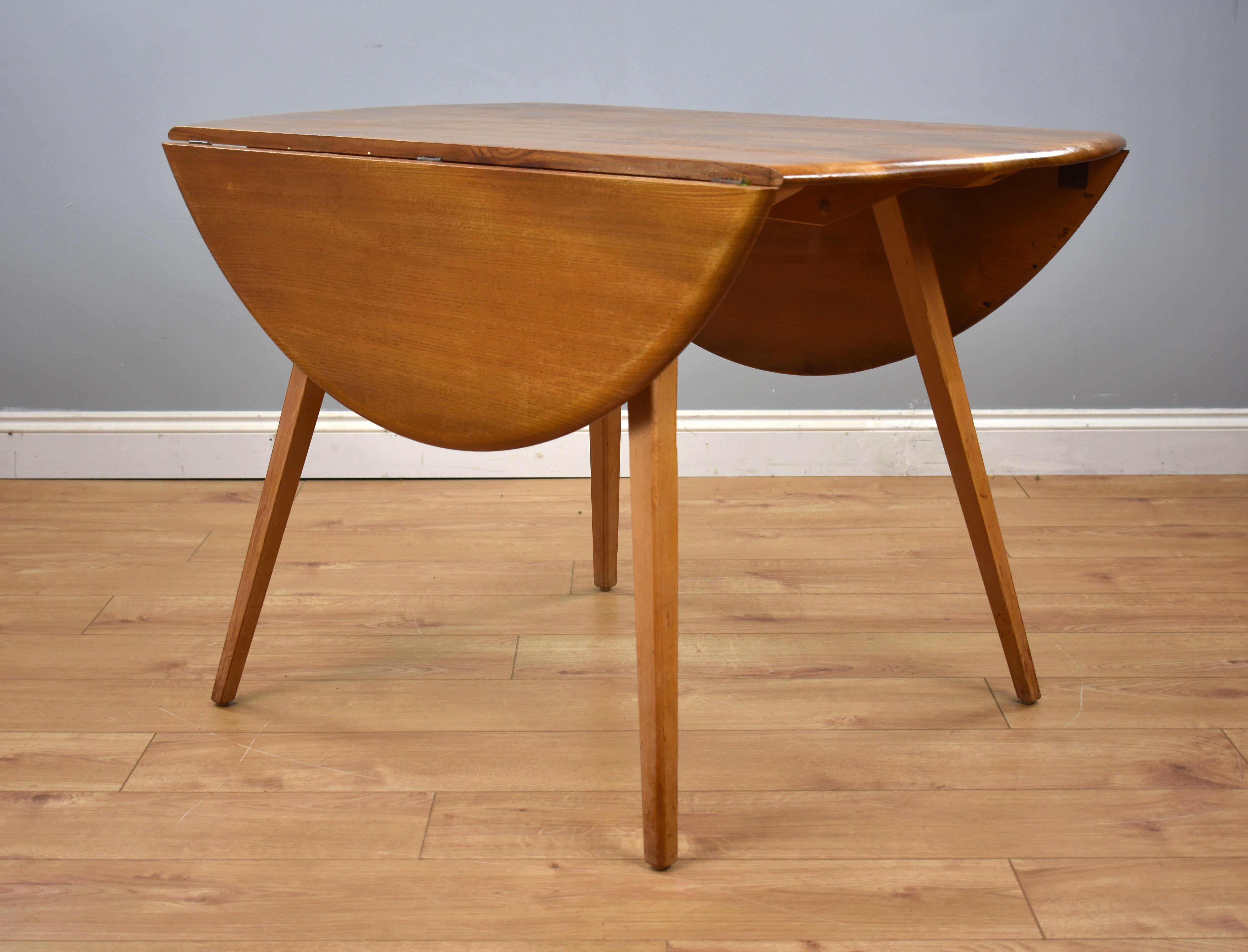 For sale is a midcentury Ercol elm dining table and 4 chairs. The elm dining table, model no. 384, having two drop leaves, standing on fine legs comes complete with four Ercol Quaker back dining chairs. The set is in very good condition for its age,
