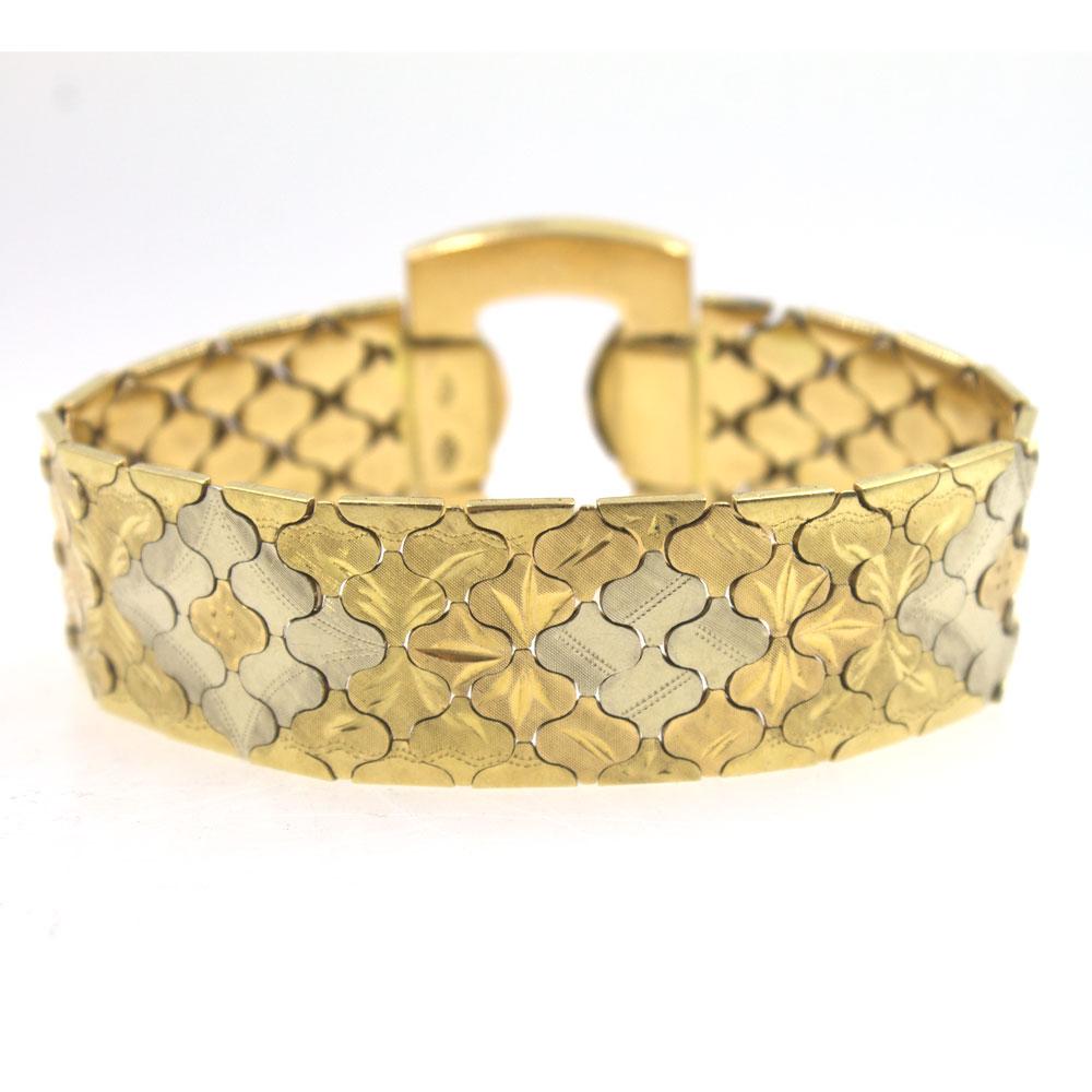 This flexible two tone bracelet is circa 1960's. Fashioned in 18 karat gold etched links and a fold over the clasp, the bracelet measures 7.5 inches in length and .80 inches in width (1.25 inches at the buckle). 