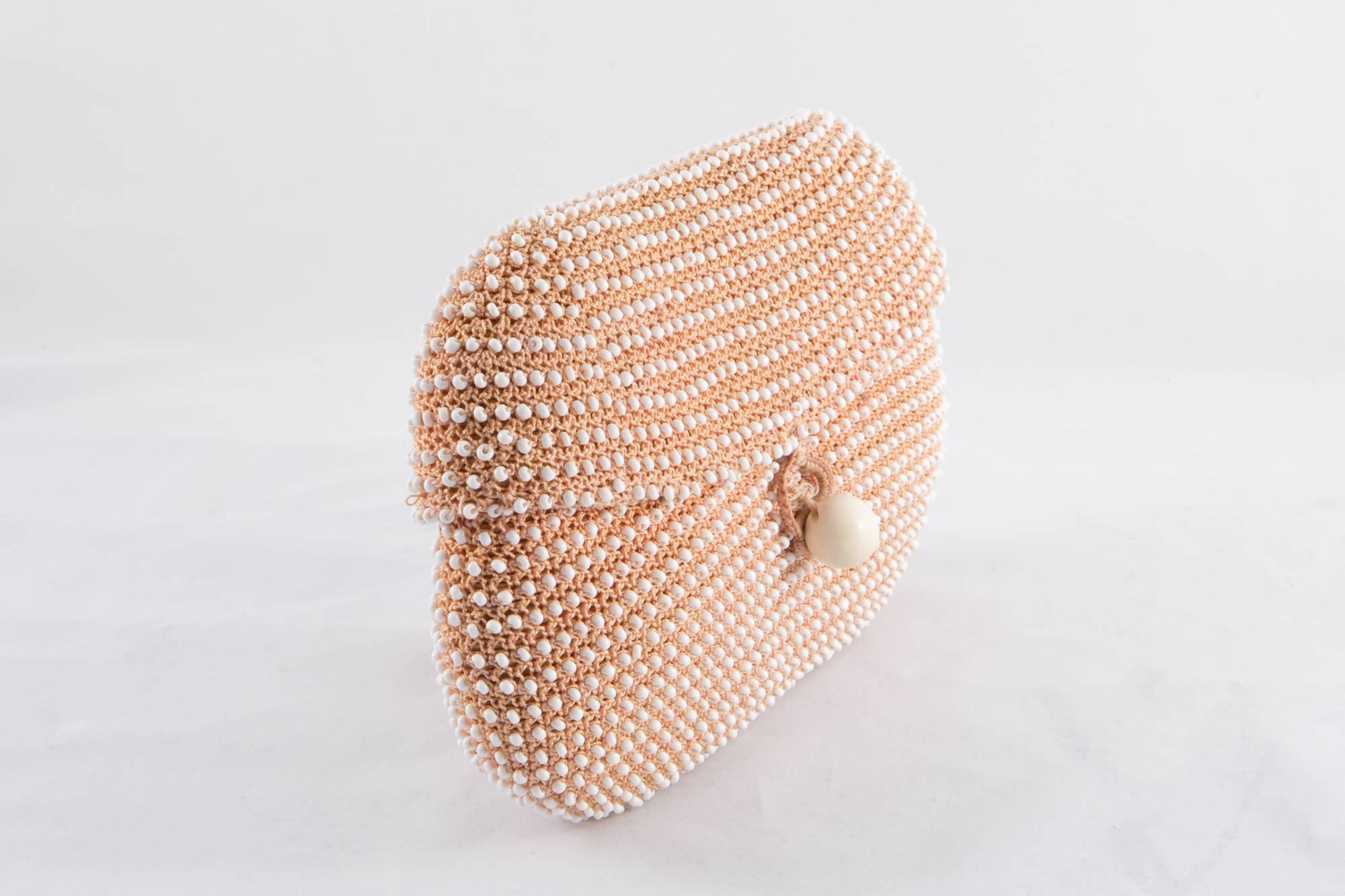 1960s camel crochet and white beaded evening clutch bag featuring a pink silk lining, a crochet loop and a large pearl button closure.
In excellent vintage condition. Made in Italy.
Measurements: 9.05in. (23cm) X 6.2in. (16 cm) X Depth 1.18in. (3cm)