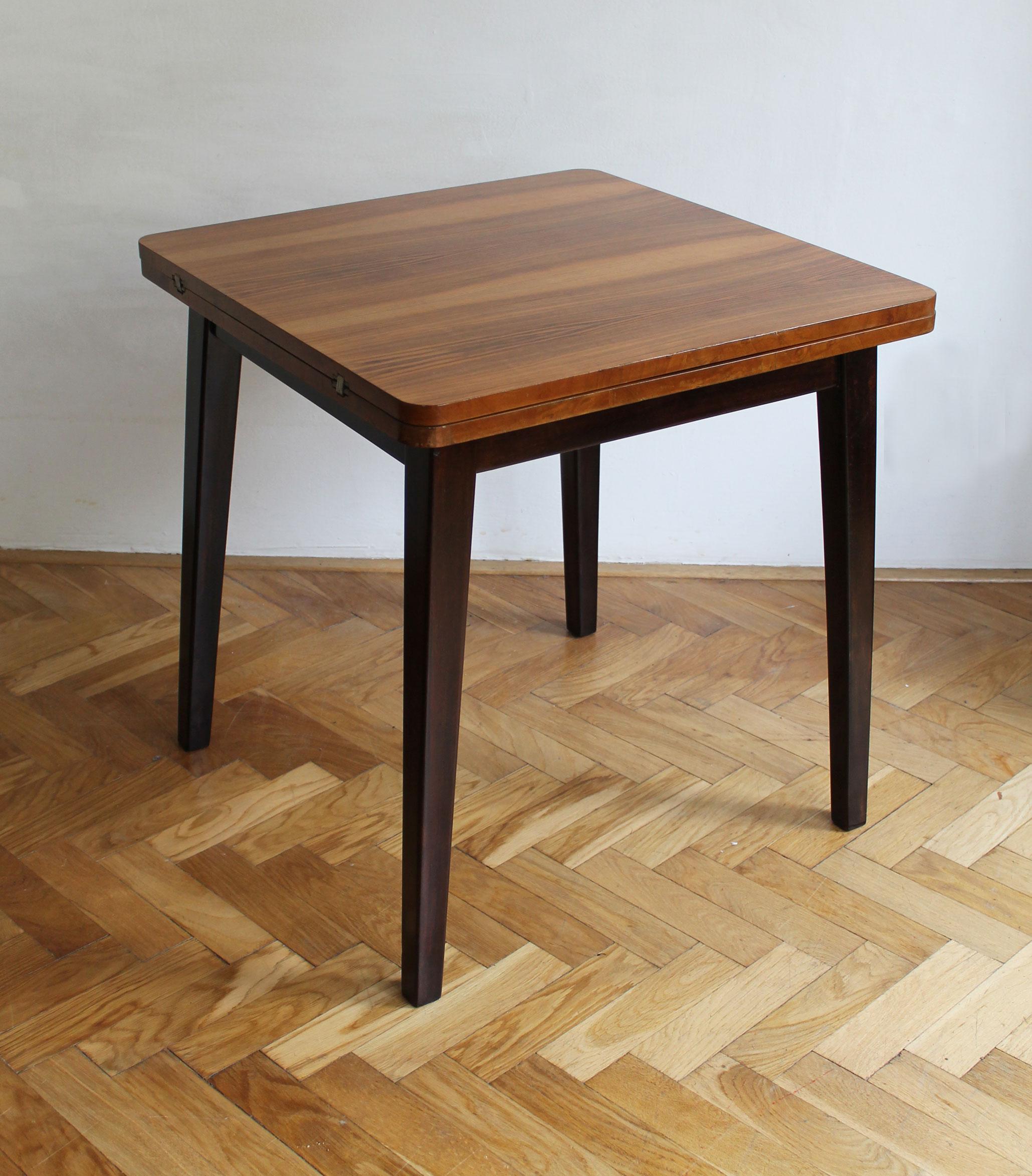 This is an original extendable side/coffee table consists of a solid wood table top which has a beautiful walnut veneer and legs made of dark brown stained Beechwood. It operates as an extendable table, with a full length of 132 cm. The main design