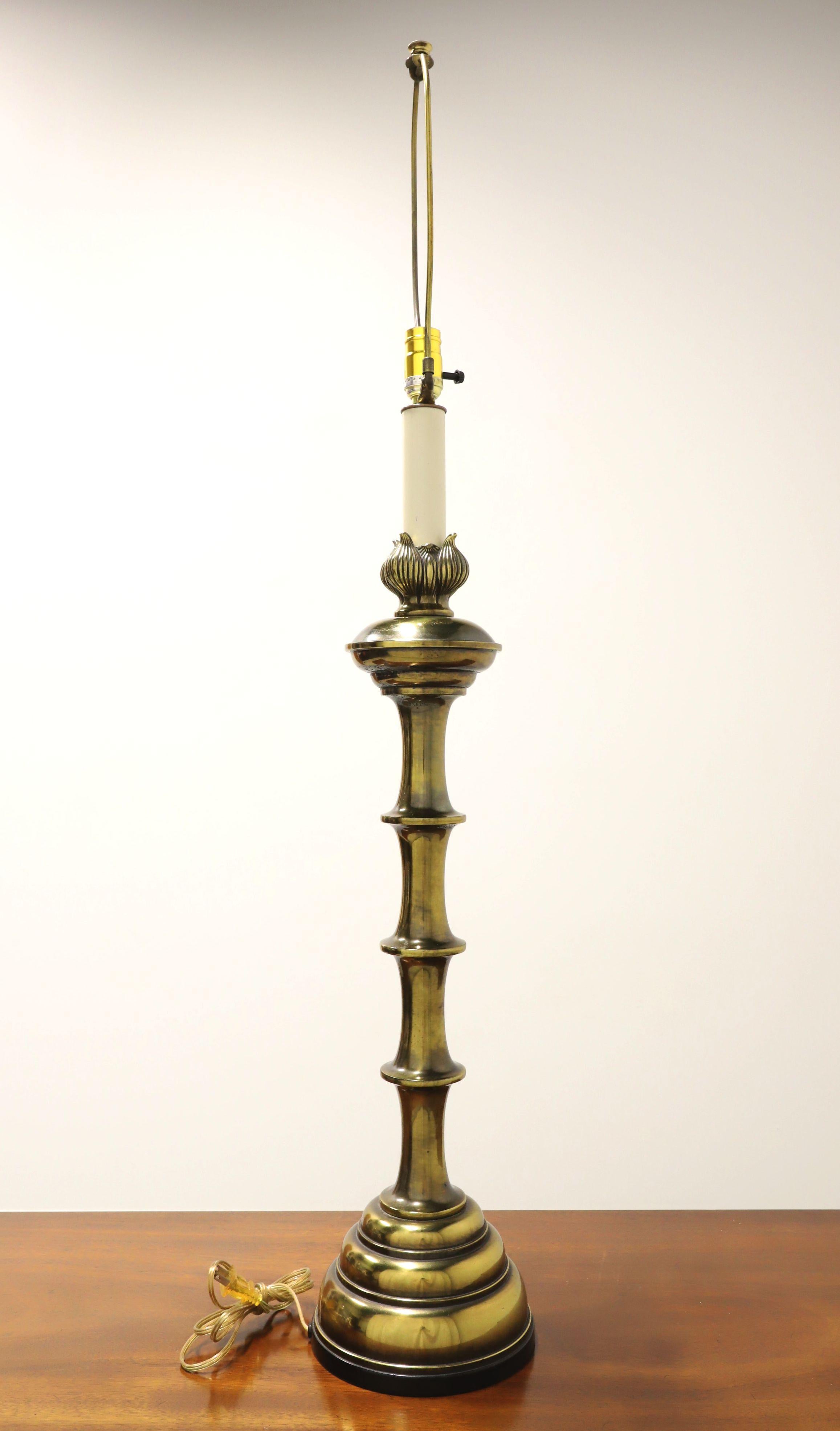 A Mid-20th Century style table lamp, unbranded. Made of solid brass with a candlestick shape, distinctive faux bamboo like design, decoratively molded top with white neck, and a brass base. Has a removable metal harp and brass cap finial. Single