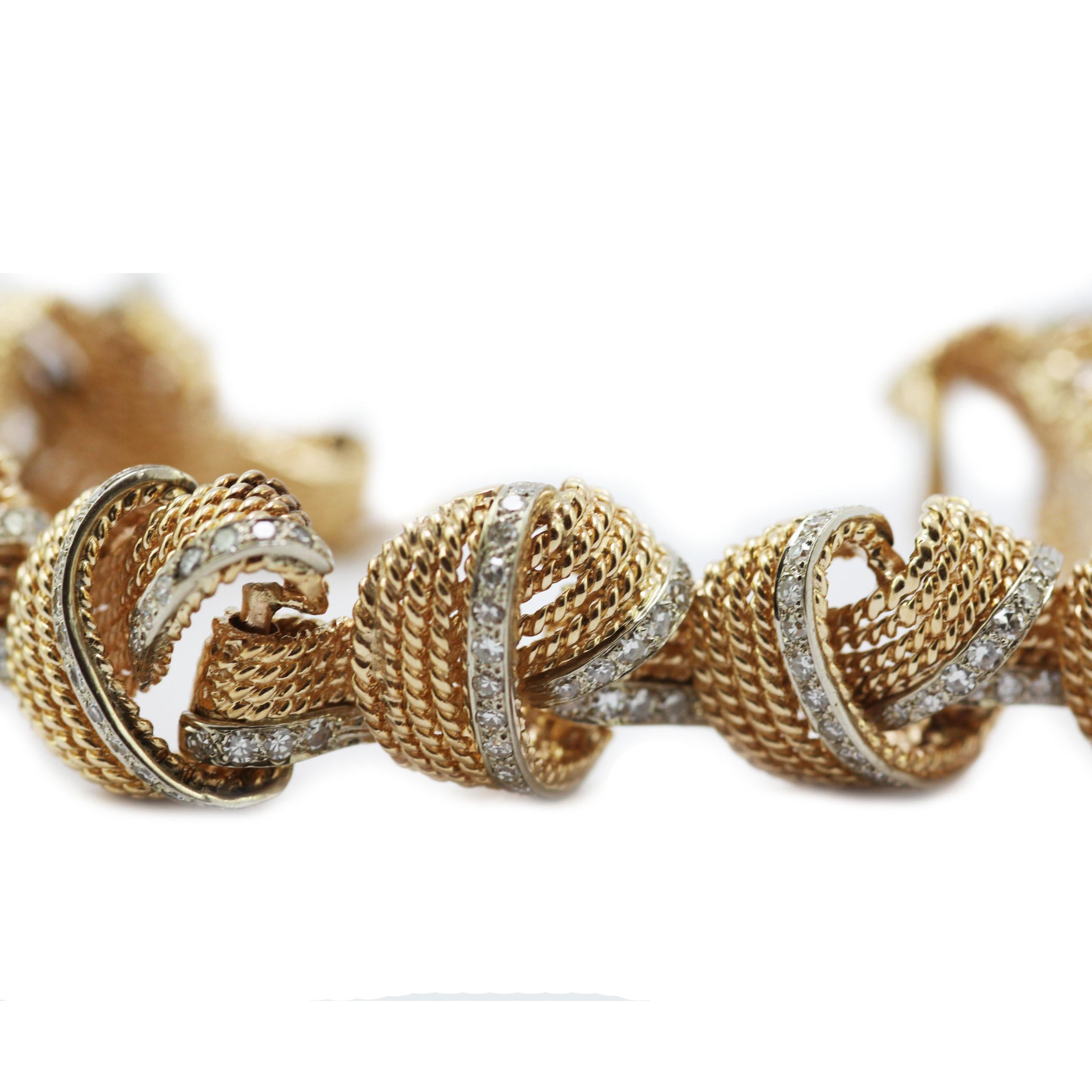 A graceful gold knot bracelet interwoven with rows of sparkling diamonds. The bracelet is formed of strands of 18 carat yellow gold woven into loose knots, intertwined with diamonds. The bracelet has a double locking safety clasp. 
207 x  round
