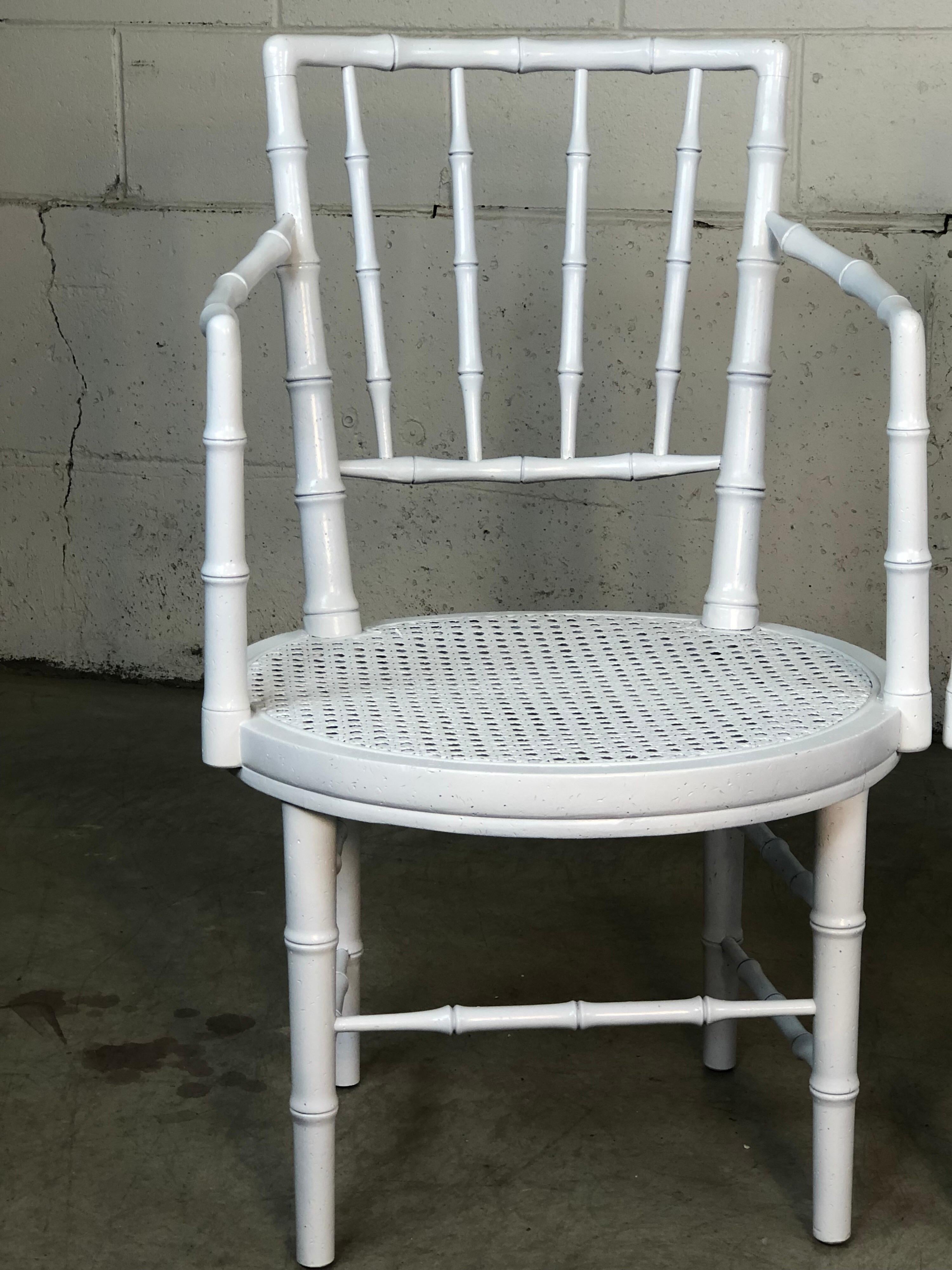 Vintage 1960s faux bamboo campaign style white lacquered arm chairs. These delicate chairs have a caned round seat and a rounded back for comfort. Fully restored condition. No marks.