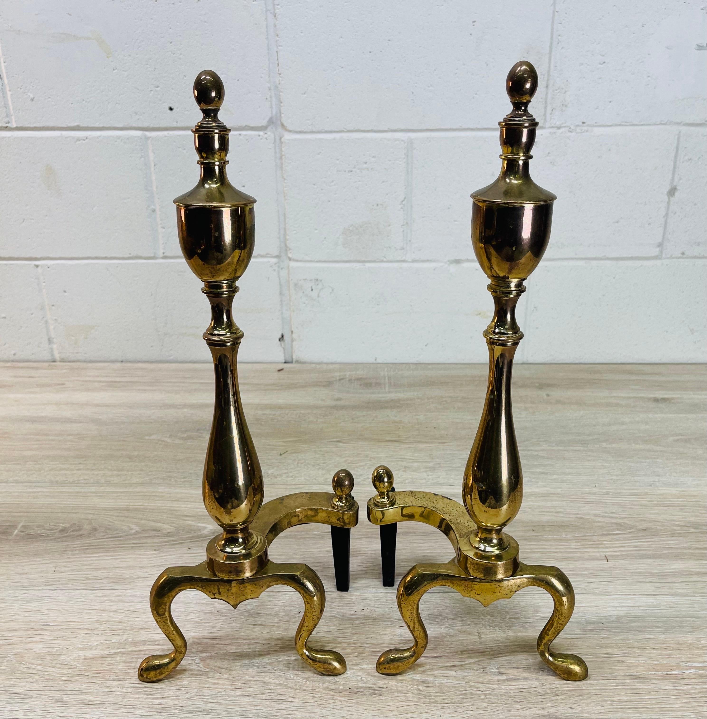 Vintage 1960s pair of brass Federal style andirons. The andirons are for decoration only and do not hold any wood. Light tarnish from age and use. No marks.
