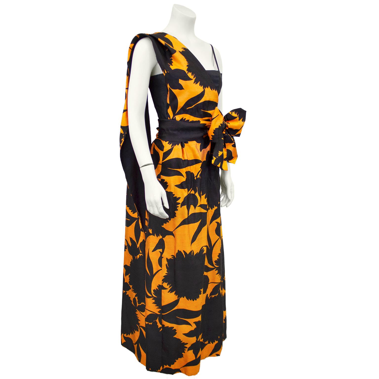 Beautiful French demi couture slubbed silk gown from the 1960's. Striking contrasting combination of orange and black. Black fitted corseted bodice with thin straps. Tea length skirt features an orange background with a black floral silhouette all