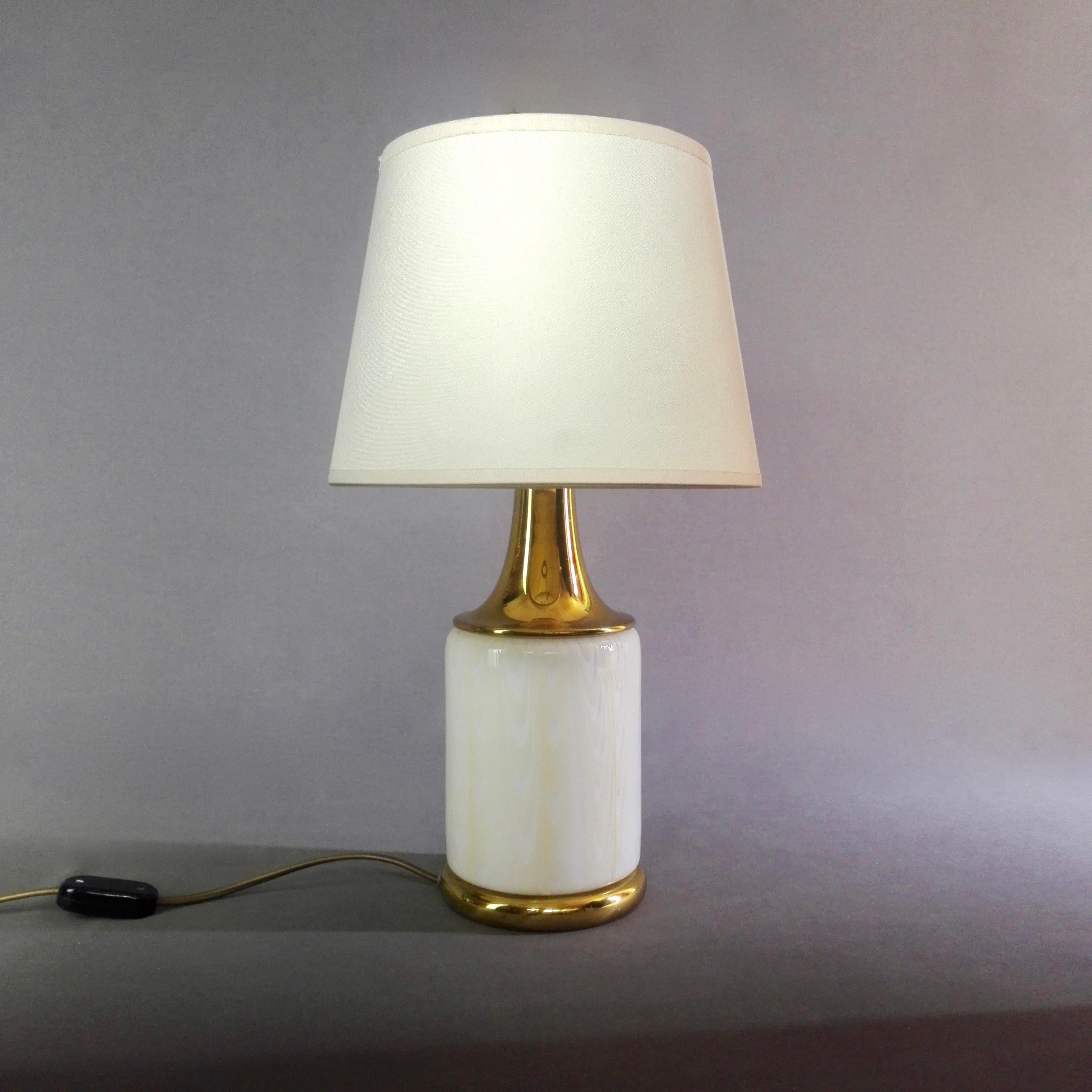 A fine Italian two-light brass and glass table lamp from the 1960s. No trademark present but its design is attributable to F.Fabbian. The lamp consists of a solid brass base, a cylindrical Murano art glass shade worked in festoons and a brass
