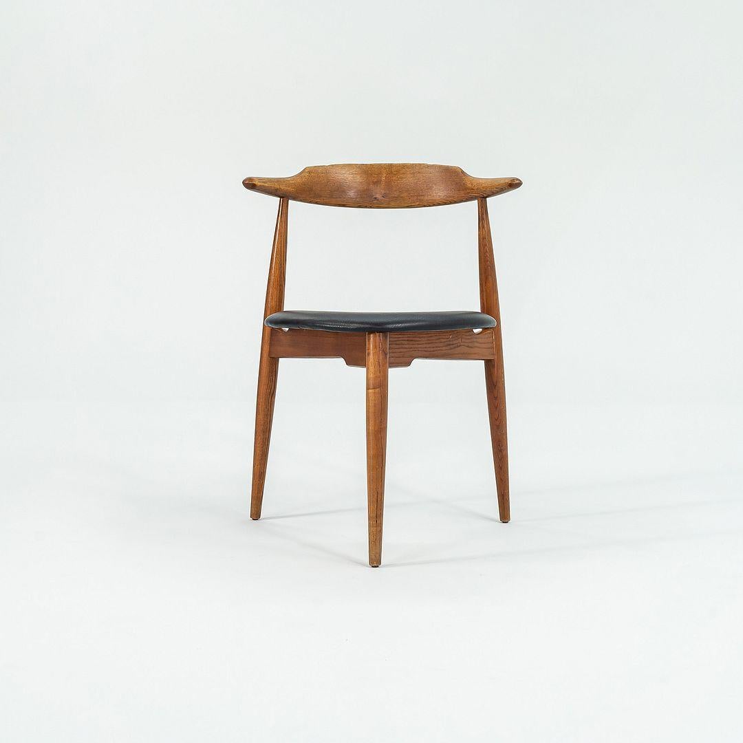 Dies ist ein FH4104 Heart Chair, ursprünglich entworfen von Hans Wegner im Jahr 1952. Dieses Exemplar wurde in den 1960er Jahren von Fritz Hansen in Dänemark hergestellt. Das Gestell des Stuhls ist aus Eichenholz und der Sitz ist mit schwarzem Leder