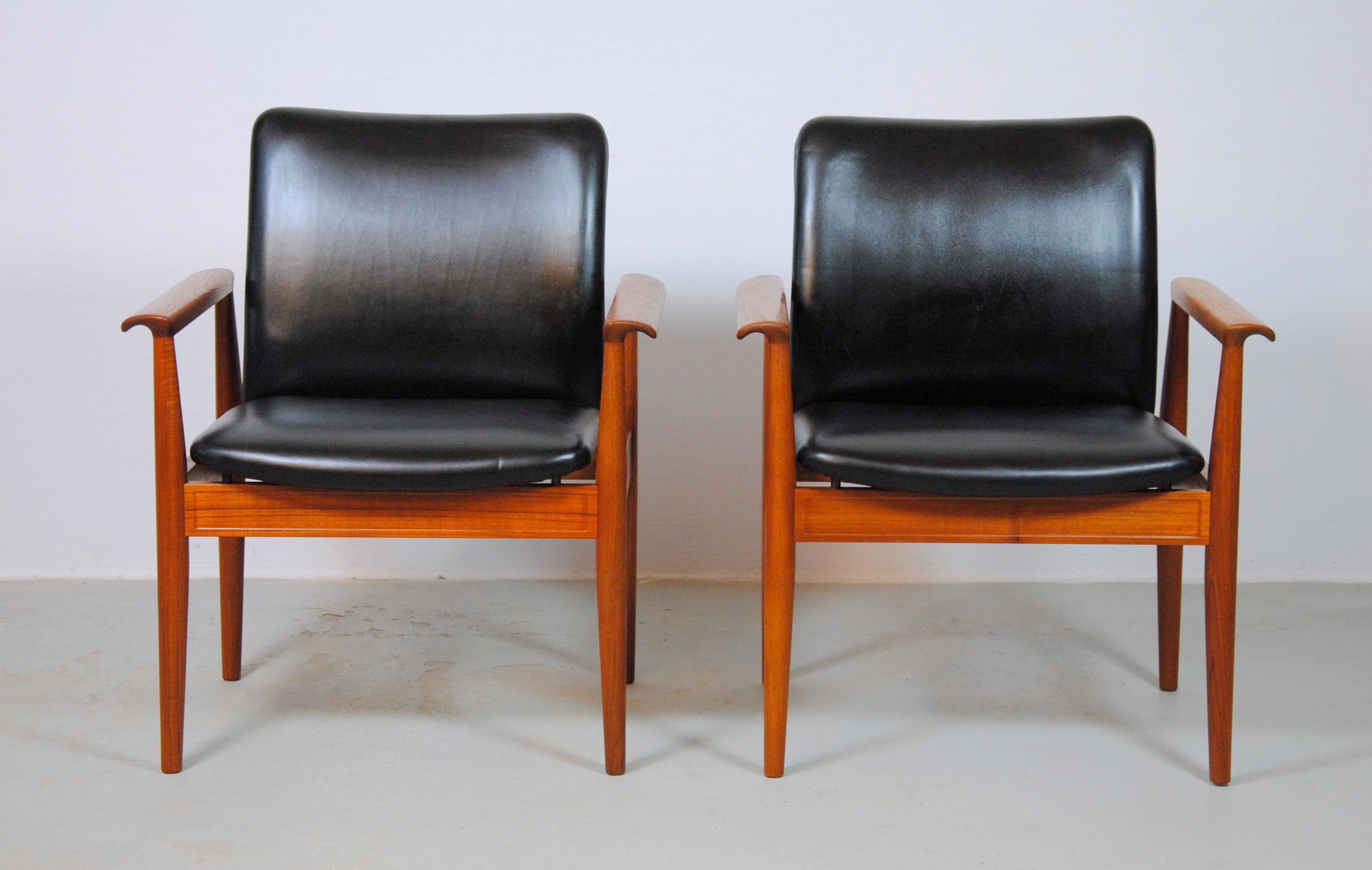 Set of two Finn Juhl armchairs in Bangkok teak and black leather designed in 1963 and made by France and Son / Cado in the 1960s

The armchairs have a solid stabile frame in teak and comfortable seats in black leather. 

Frames of the chairs