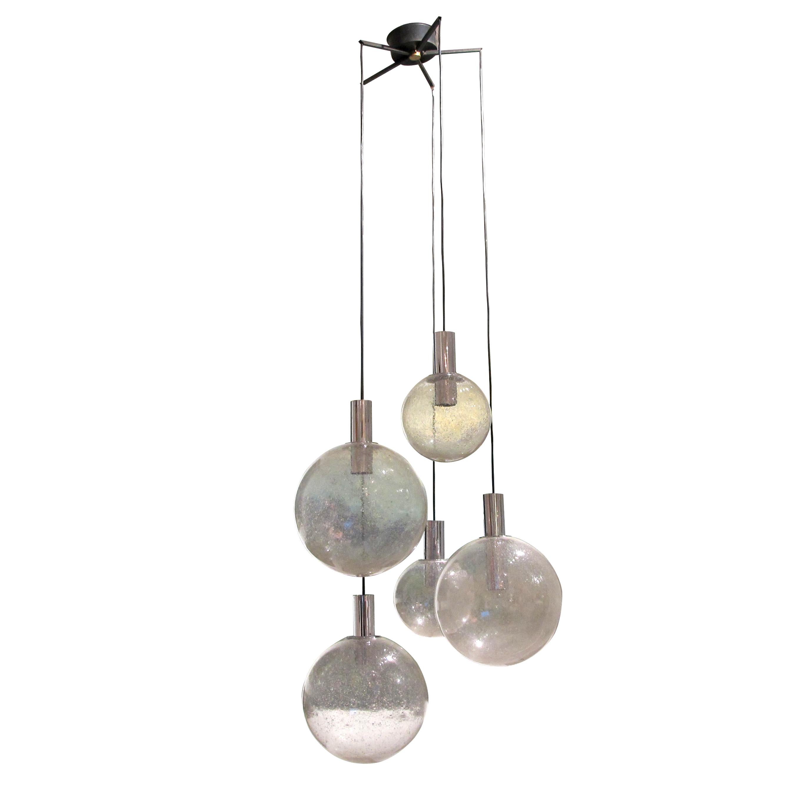 This 1960s large pendant light by Doria Leuchten is a perfect example of the mid-century modern style. The light features six hand-blown glass globes in various sizes and shapes, which are suspended from black wires on a chrome-finished metal frame.