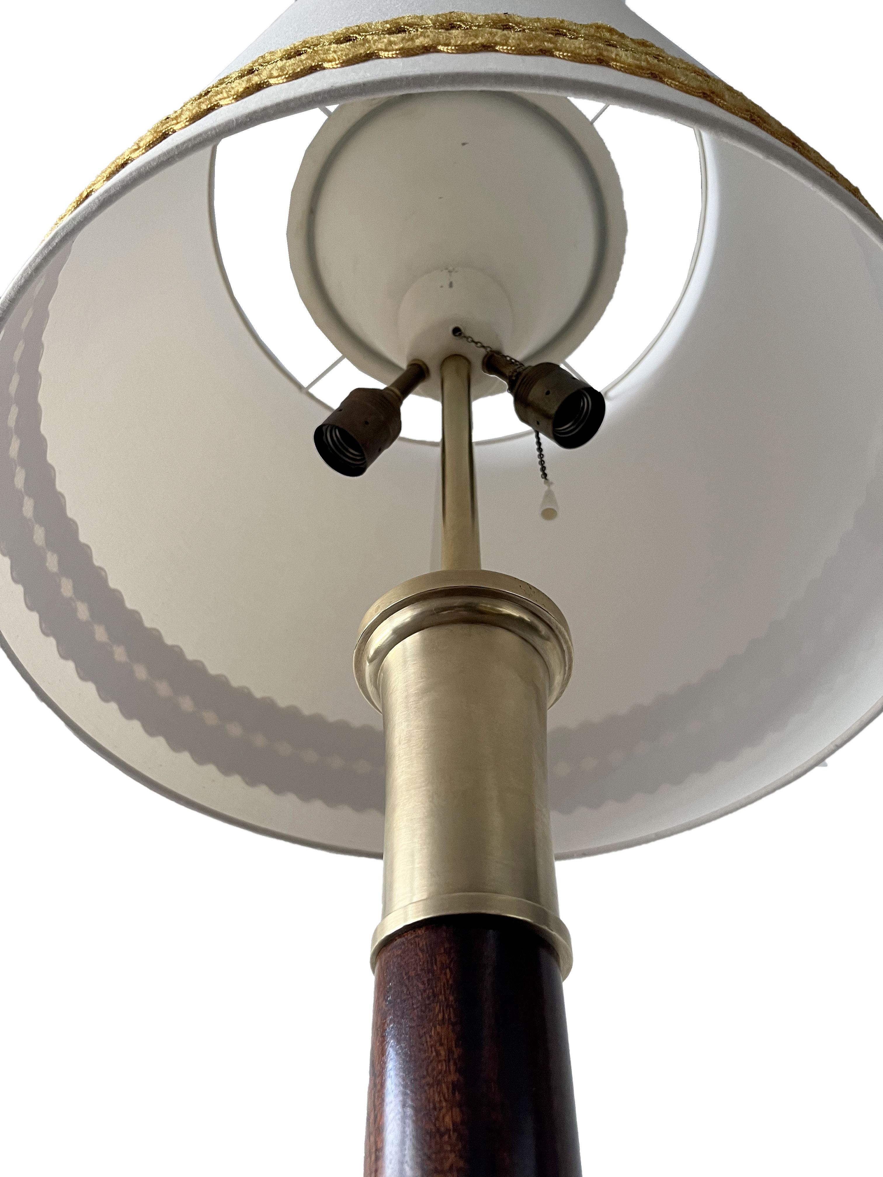 This floor lamp is made of solid mahogany with a French polyurethane finish and polished brass accents. It features two light sources and comes with a new lampshade designed to resemble the original design, with beige fabric.

The lamp was made by
