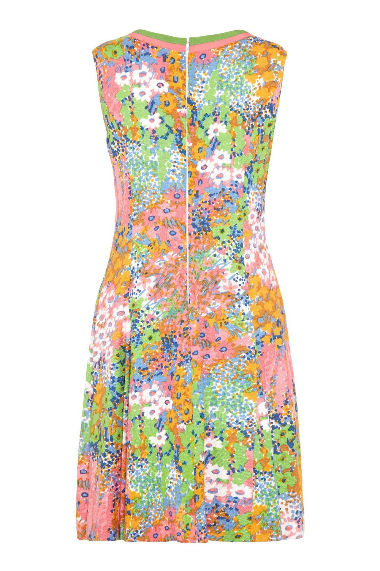 This pretty linen floral print shift dress was designed in the 1960s. Its fresh, buoyant print reveals painterly florals in vibrant pastel hues of pink, orange, blue and meadow green. Featuring a V-neckline trimmed in contrasting green and sugar