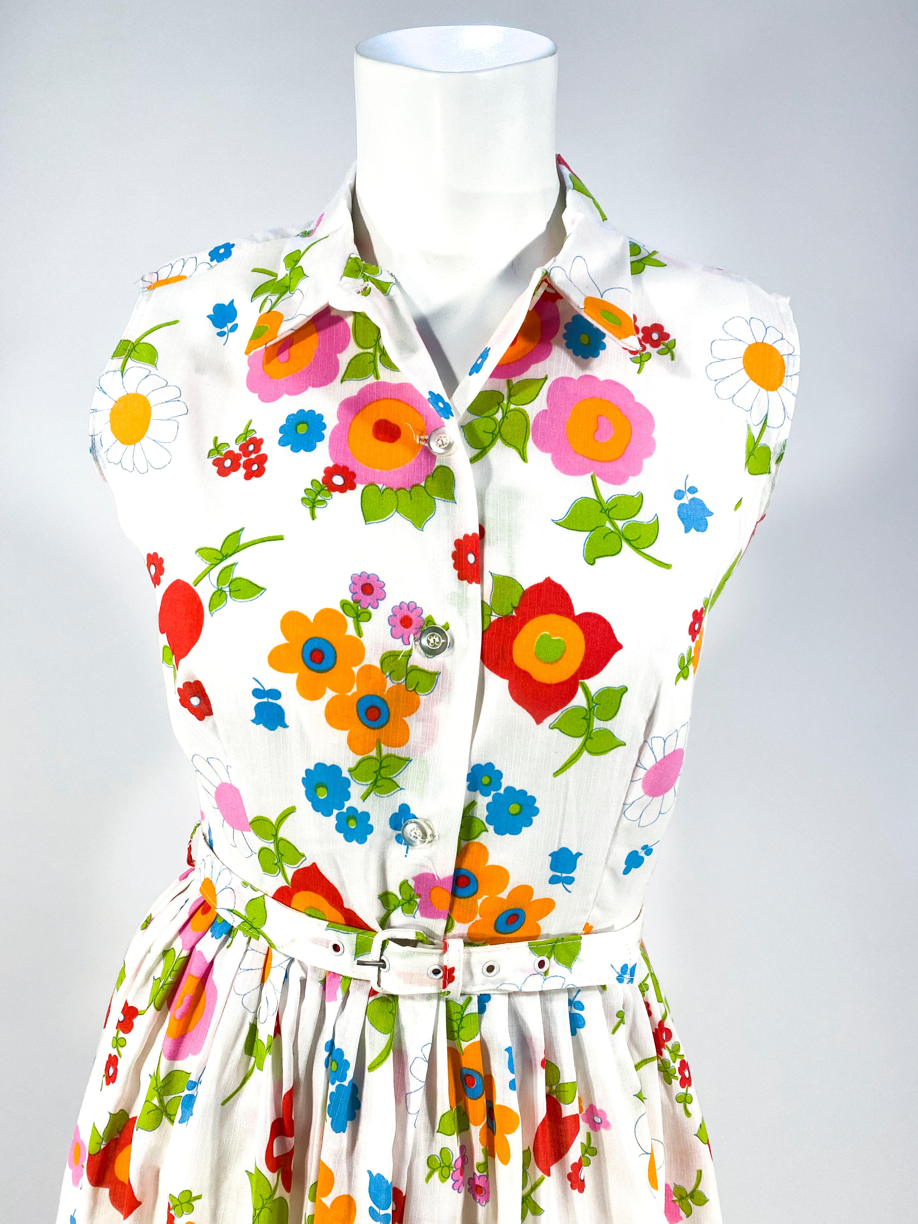 1960s Polyester and rayon blend day dress featuring a floral print in tones of reds, greens, pinks, oranges, and blues on a white field. The dress has the original tags and matching belt . The white fabric has a faint pinstripe. The neck has a Peter