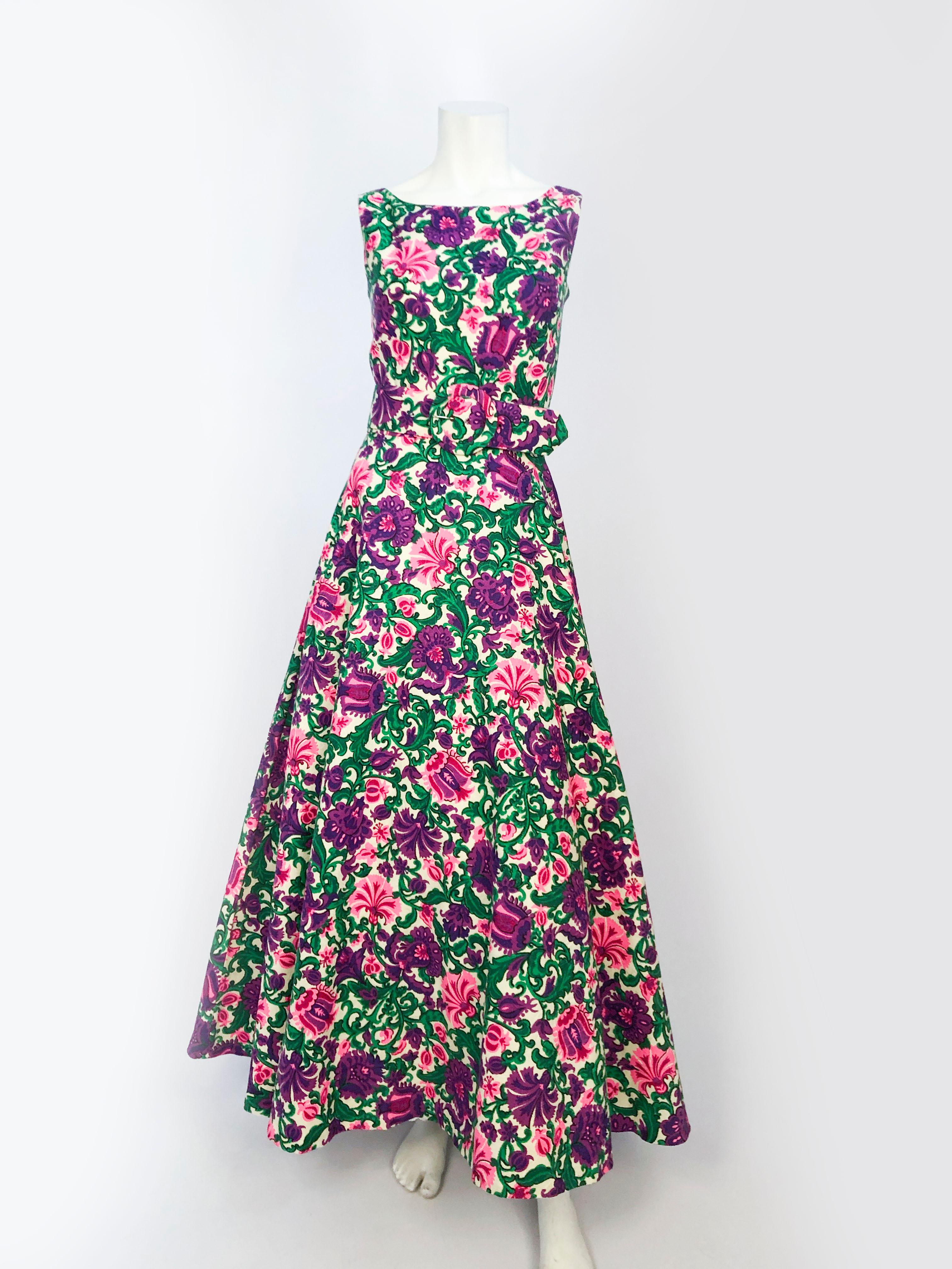 1960's vibrantly printed dress featuring a floral pattern on jacquard. This dress has a scoop neckline, a full skirt, matching belt, and a low back zipper closure. This dress was styled with a petticoat that is not included with the dress.