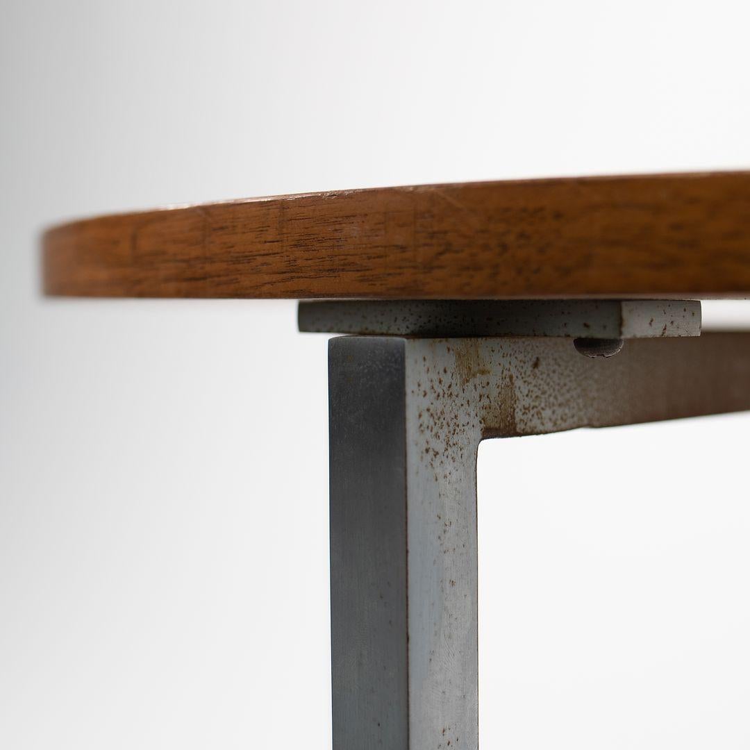 This is a pair of walnut and steel circular end tables, designed by Florence Knoll for Knoll International in the 1960s. They feature round walnut tops supported by steel bases. The bases have a brushed nickel finish. This handsome pair is perfect