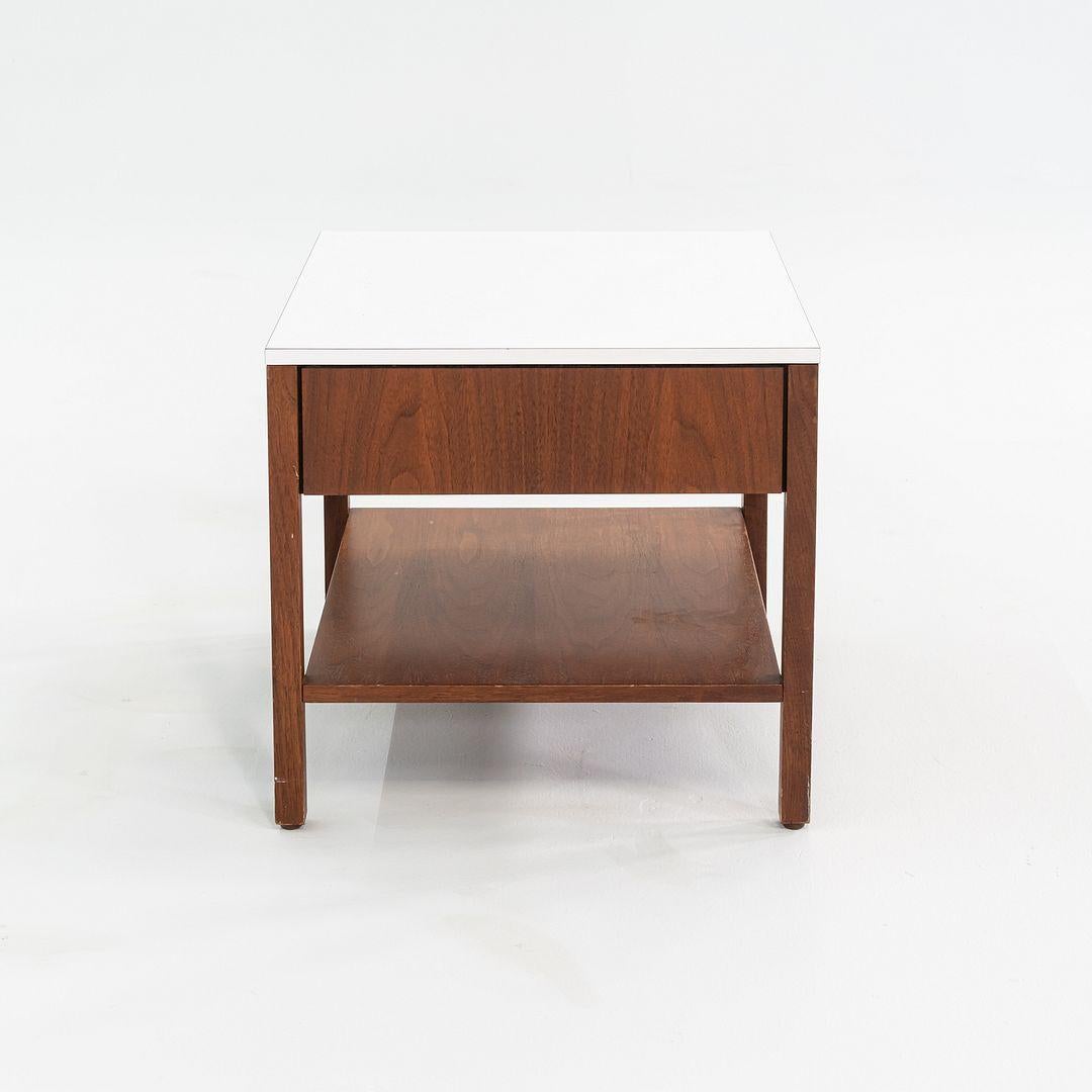 This is a walnut bedside table, Model 327 IS, designed by Florence Knoll in 1956. This particular example dates to the 1960s and has a white laminate top. The design features a walnut case with one drawer above a lower shelf.
 
 The table measures