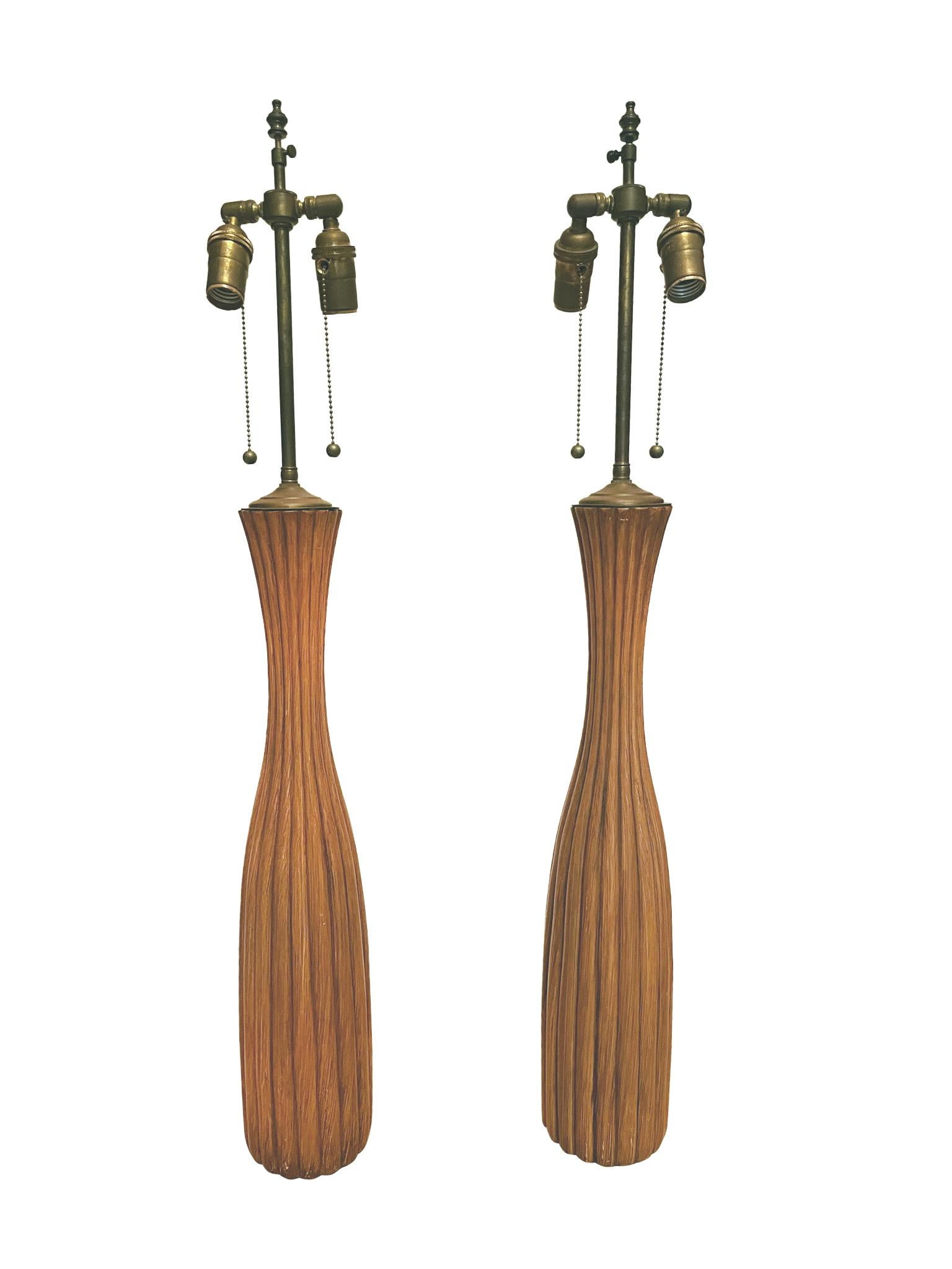 Originally crafted in the 1960s, these table lamps are teak with an elegant fluted design and warm sepia tone. They are newly rewired and custom-fitted with new linen shades. Each lamp has double sockets with pull strings. Simple in structure, these
