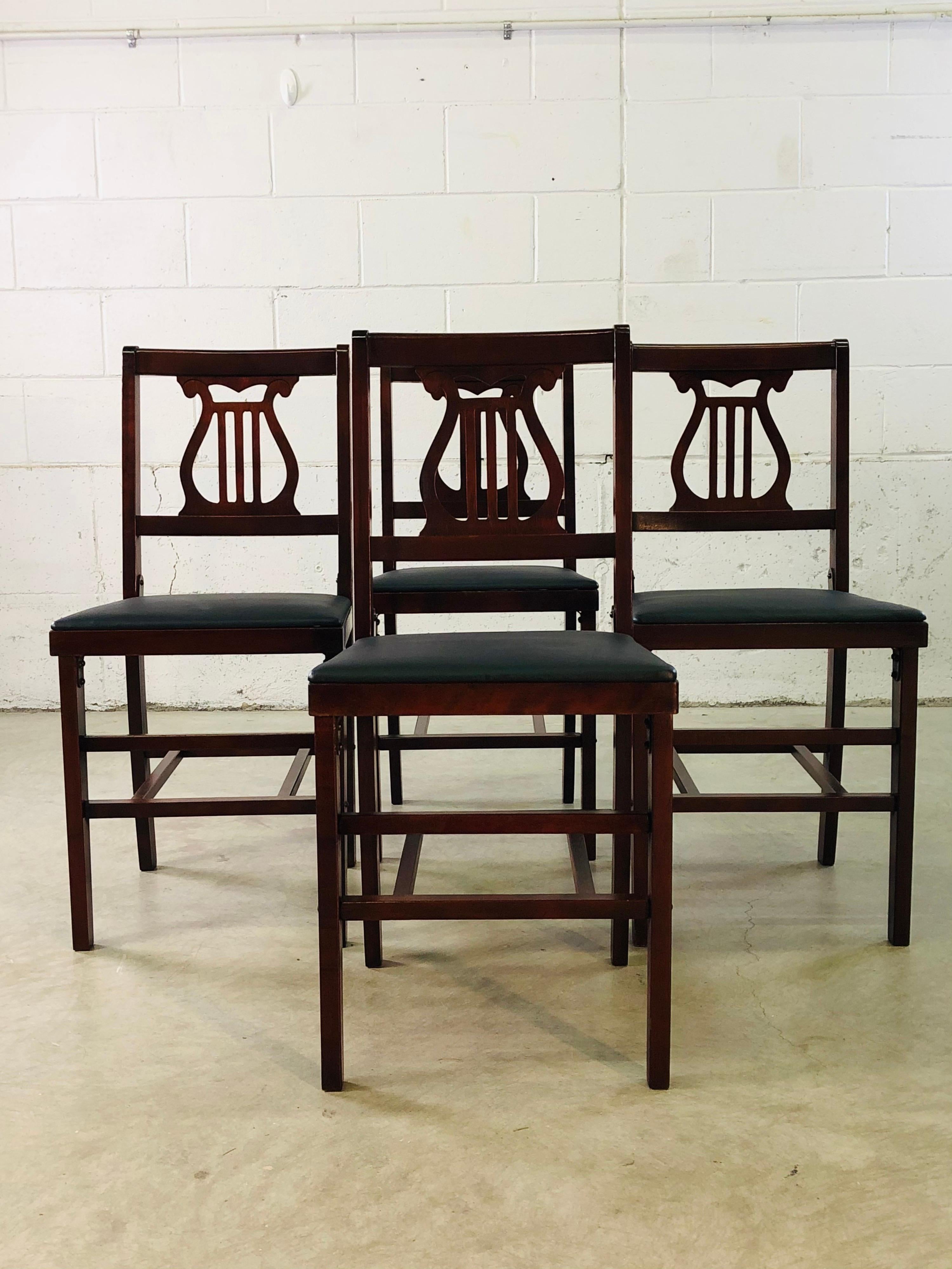 Vintage 1960s set of 4 mahogany wood folding dining chairs. The chairs have new black naugahyde seats and fold up for storage. Great for an apartment or small space. Excellent condition.