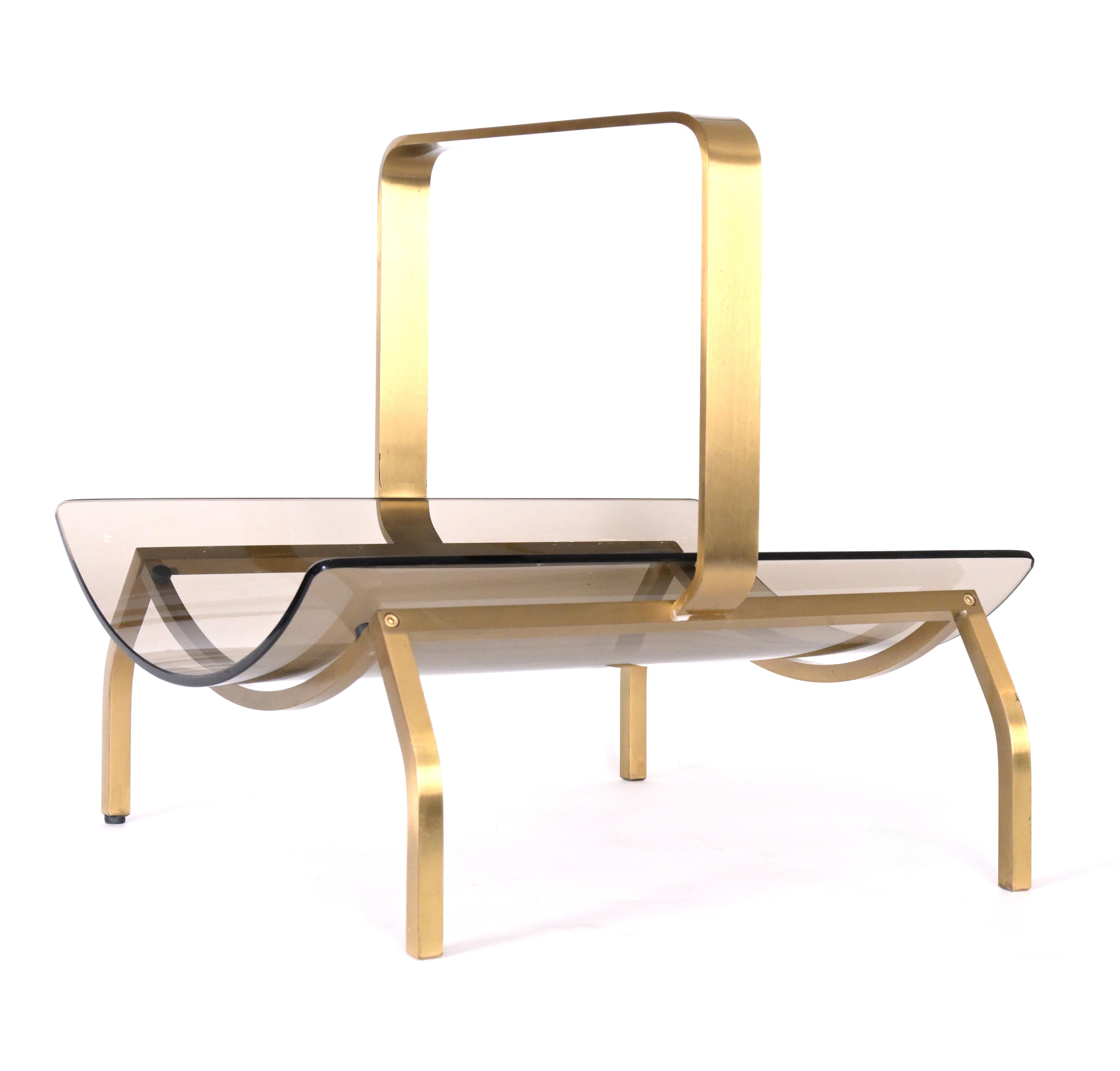 A smoked glass magazine rack with a curved brass frame featuring tapered legs and handle. From the 1960s-1970s made by the Italian design company Fontana Arte (1881-).