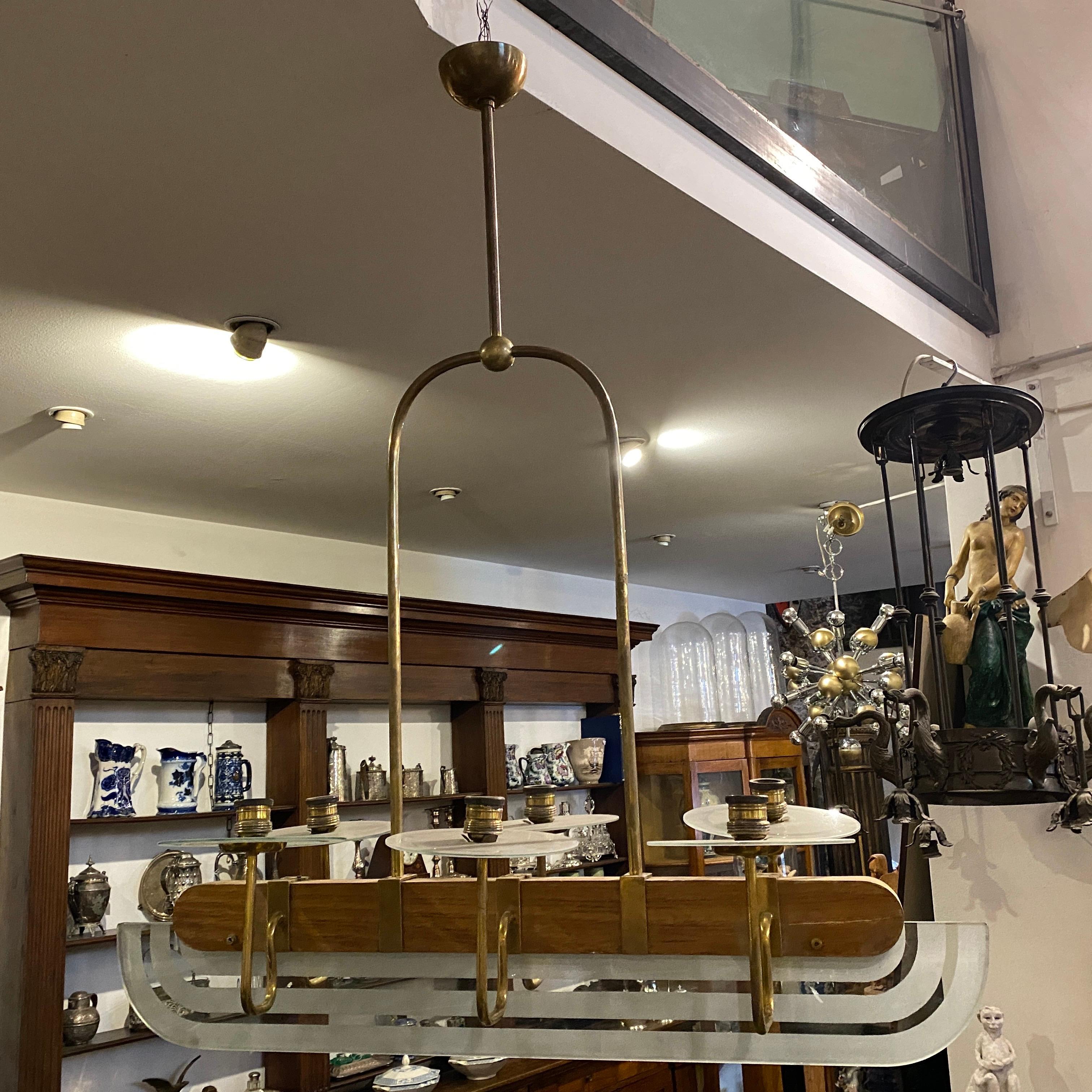 An elegant six lights oval chandelier in original conditions, heavy glass, wood and brass are in perfect conditions. It works 110-240 volts and needs 6 regular e27 bulbs. It's inspired by chandelier designed by Pietro Chiesa for Fontana Arte.