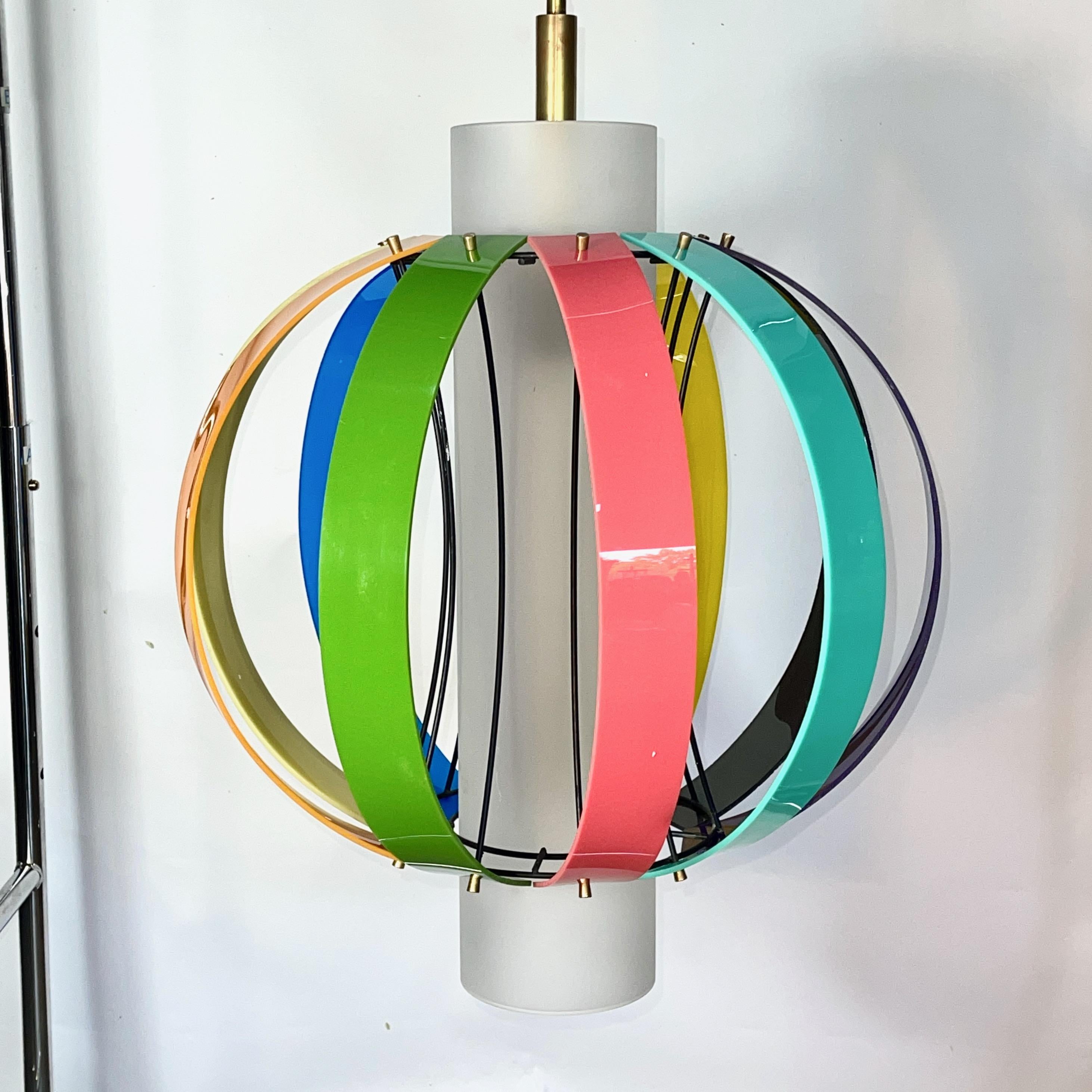 Large colorful beachball pendant light by Fredrick Ramond of California circa 1963.
Ten bands of colored acrylic secured to an enameled wire scaffold by brass screw caps floating around a satin glass cylinder held by three brass pins, within which
