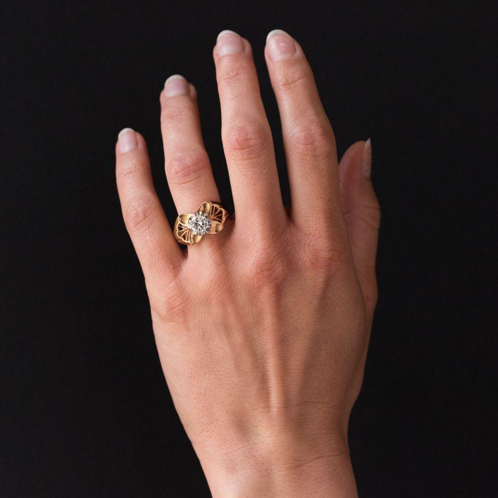 18 carat 750 thousandths rose gold ring, eagle head hallmark. 
This ring from the 1960s features a claw set antique brilliant cut diamond in an openwork fan shaped setting with 4 smooth petal motifs. The beginning of the ring band is wide and