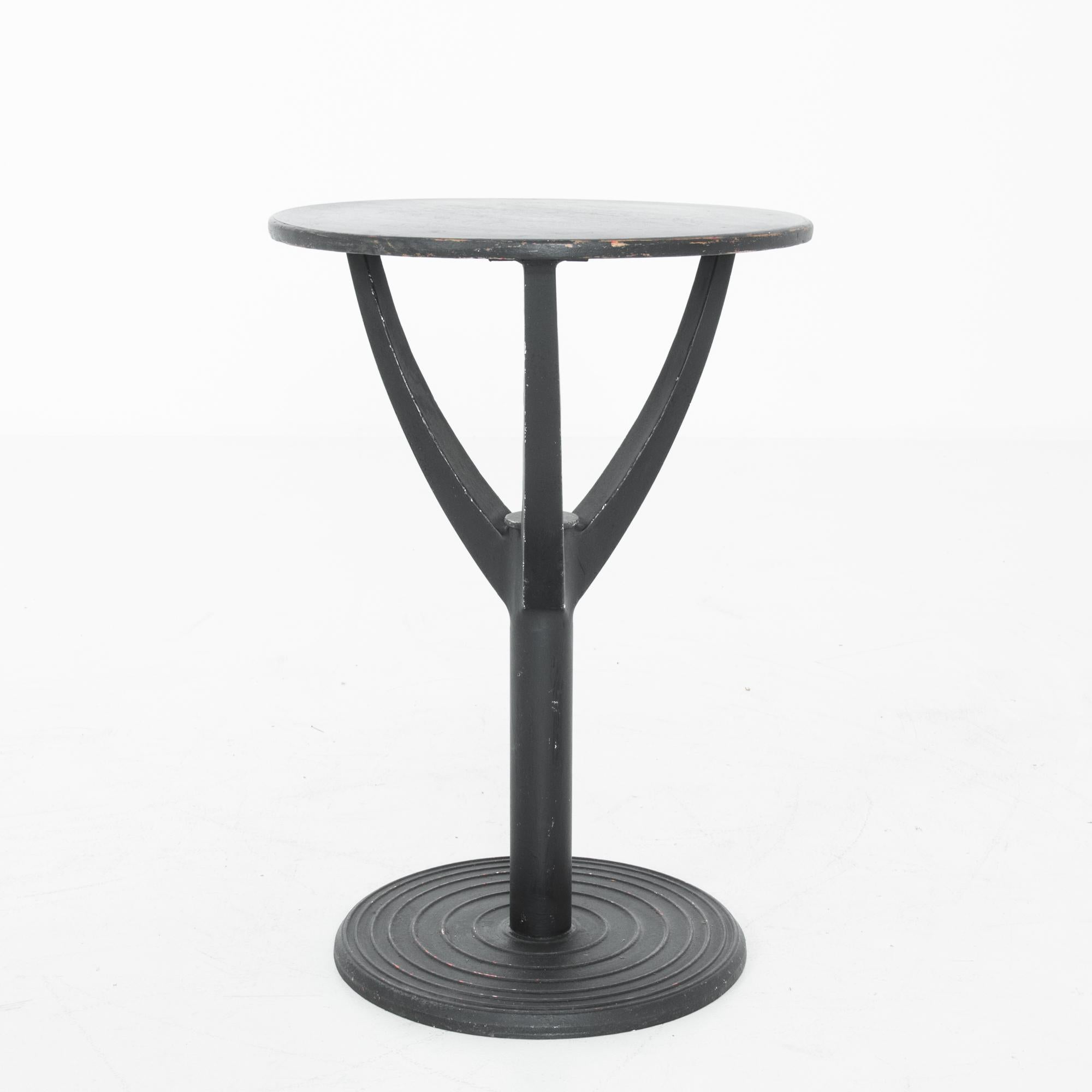 A black patinated wood & metal table from France, produced circa 1960. A striking piece, this side table features a round top held aloft on three arms springing from a central support. The concentric circles ringing the base are like ripples in the