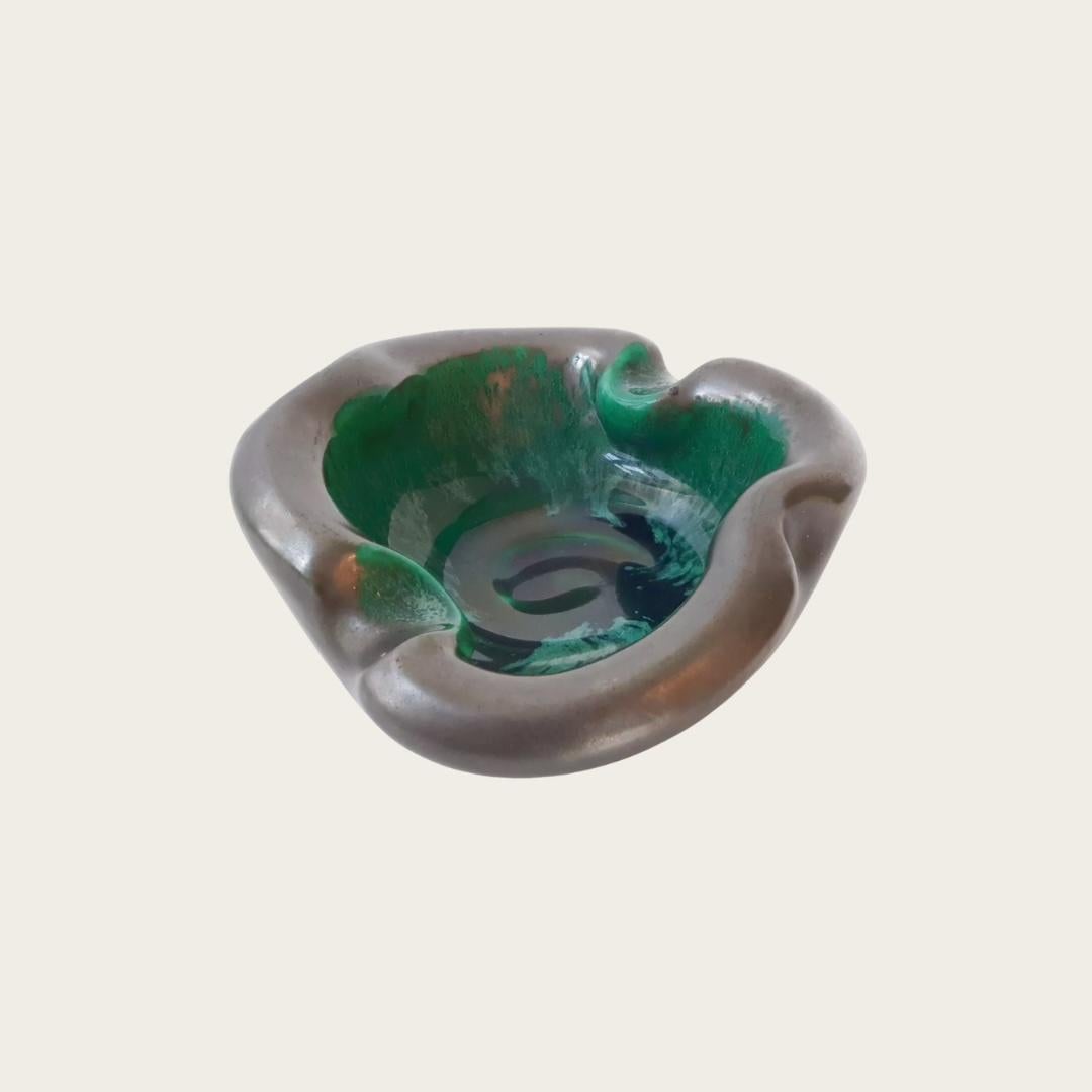 Anni '60, Francia. La vide poche in ceramica presenta un elegante smalto nero esterno abbinato a un interno verde perlato, che riflette lo stile modernista di Georges Jouve. Non segnato, l'autore esatto è sconosciuto.