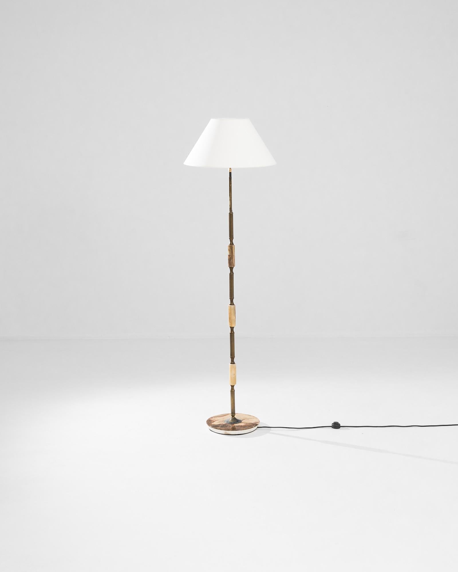 This 1960s floor lamp epitomizes Mid-Century Modern sophistication. Sourced from France, the pristine simplicity of the linear silhouette is embellished with onyx accents: the contrast between the liquid veining of the gemstone and the fluted detail
