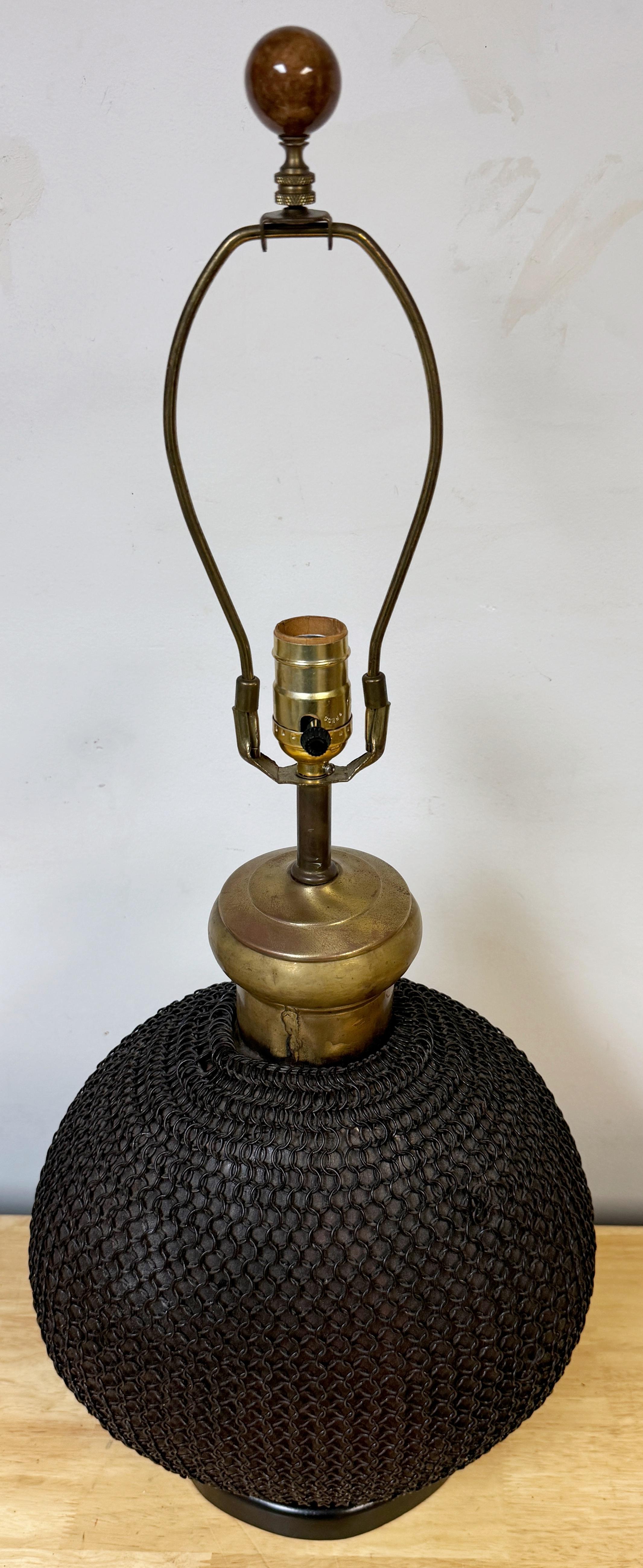 1960s French Brass & Metal Chain Mail Rounded Orb Lamp 

A unique 1960s French Brass & Metal Chain Mail Rounded Orb Lamp, embodying the creativity of mid-century design. Standing 29 inches tall to the top of the included finial and harp, this lamp