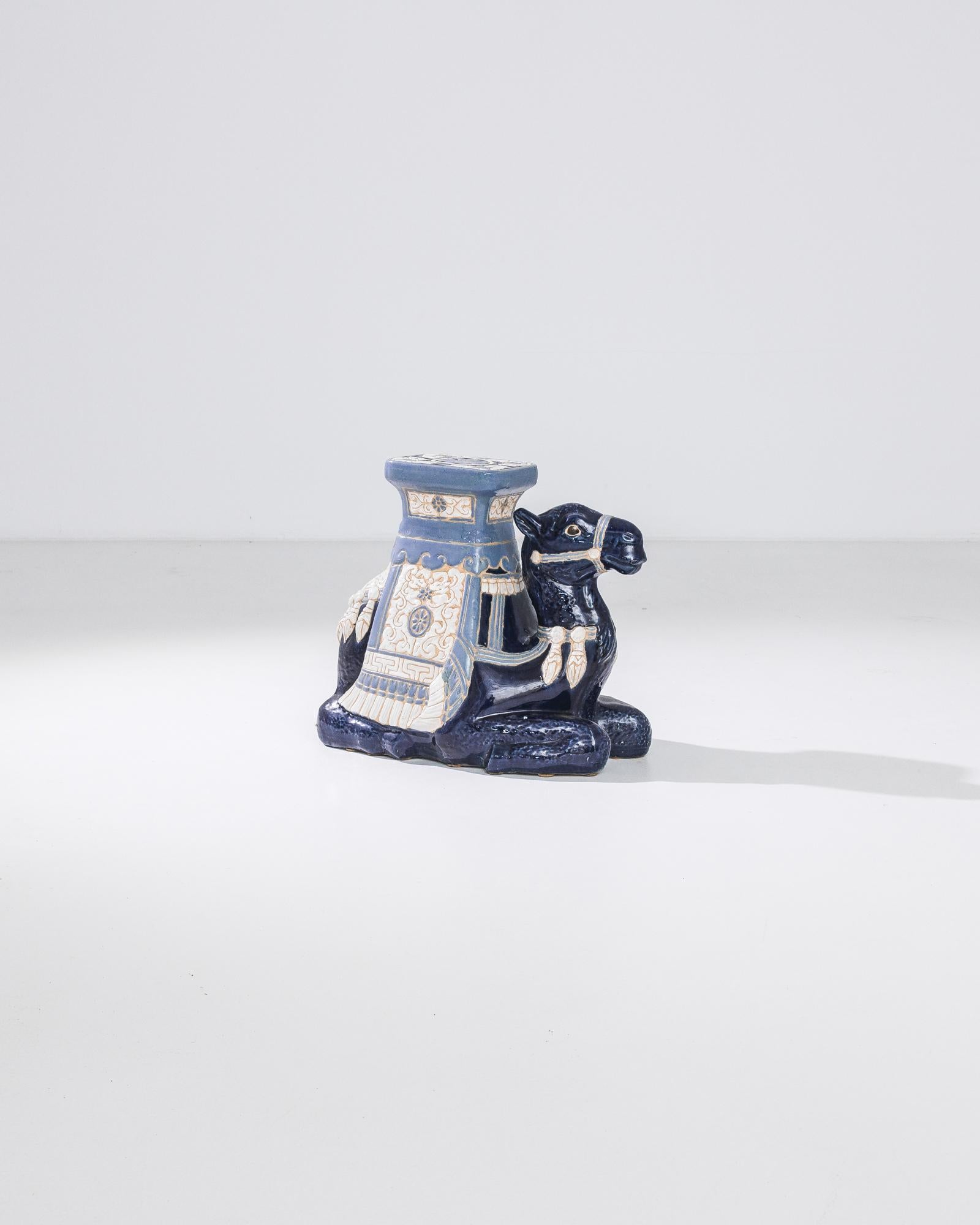 A ceramic decoration from 1960s France in the shape of a blue camel. A saddle seat and blanket are glazed with bright colors; the assortment of delicate patterns — reflecting Chinese and Arabic influences — suggest the romance of the Silk Road. The