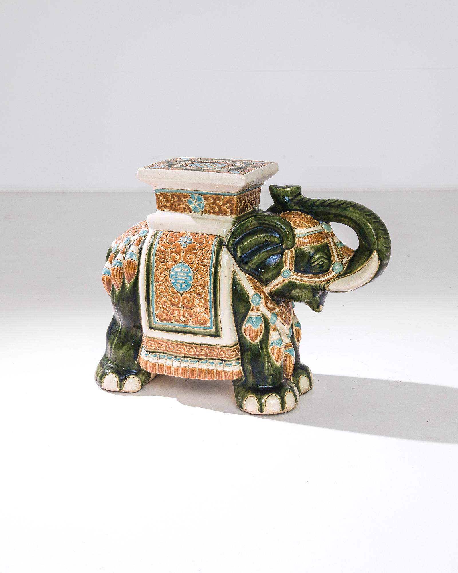 A ceramic decoration from 1960s France in the shape of an elephant. A saddle seat and blanket are glazed with celadon hues, laced with powder blue and a was of yellow ochre; the assortment of delicate patterns — reflecting Chinese and Arabic