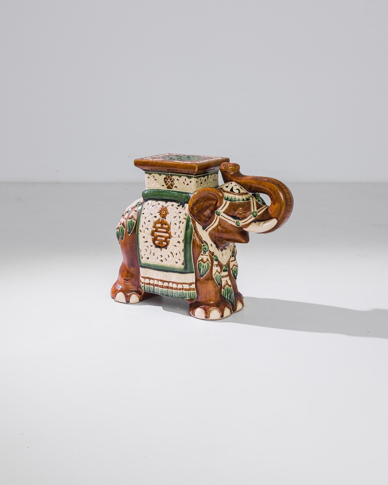A ceramic decoration from 1960s France in the shape of an elephant. A saddle seat and blanket are glazed with bright ochre and green; the assortment of delicate patterns — reflecting Chinese and Arabic influences — suggest the romance of the Silk
