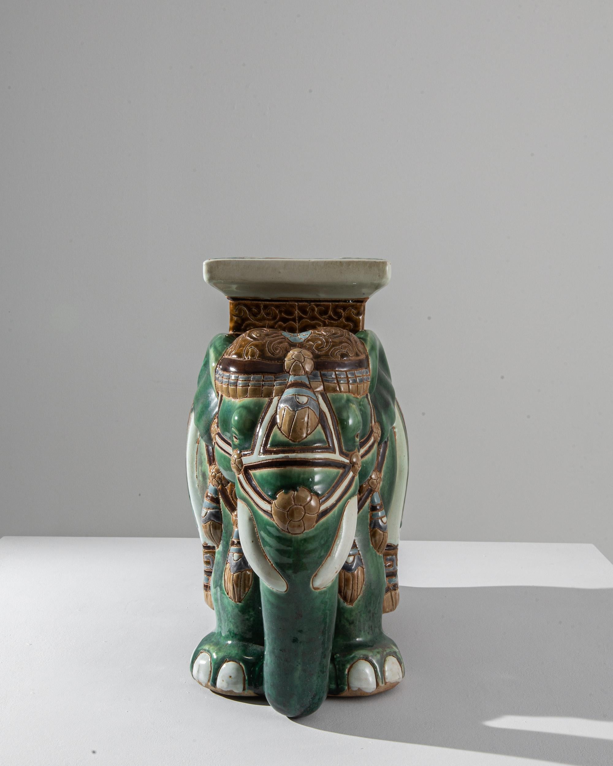 A ceramic decoration from 1960s France in the shape of an elephant. Glazed in a celadon hue laced with powder blue and yellow ochre; the saddle, seat and blanket are delicately patterned — reflecting Chinese and Arabic influences — suggesting the