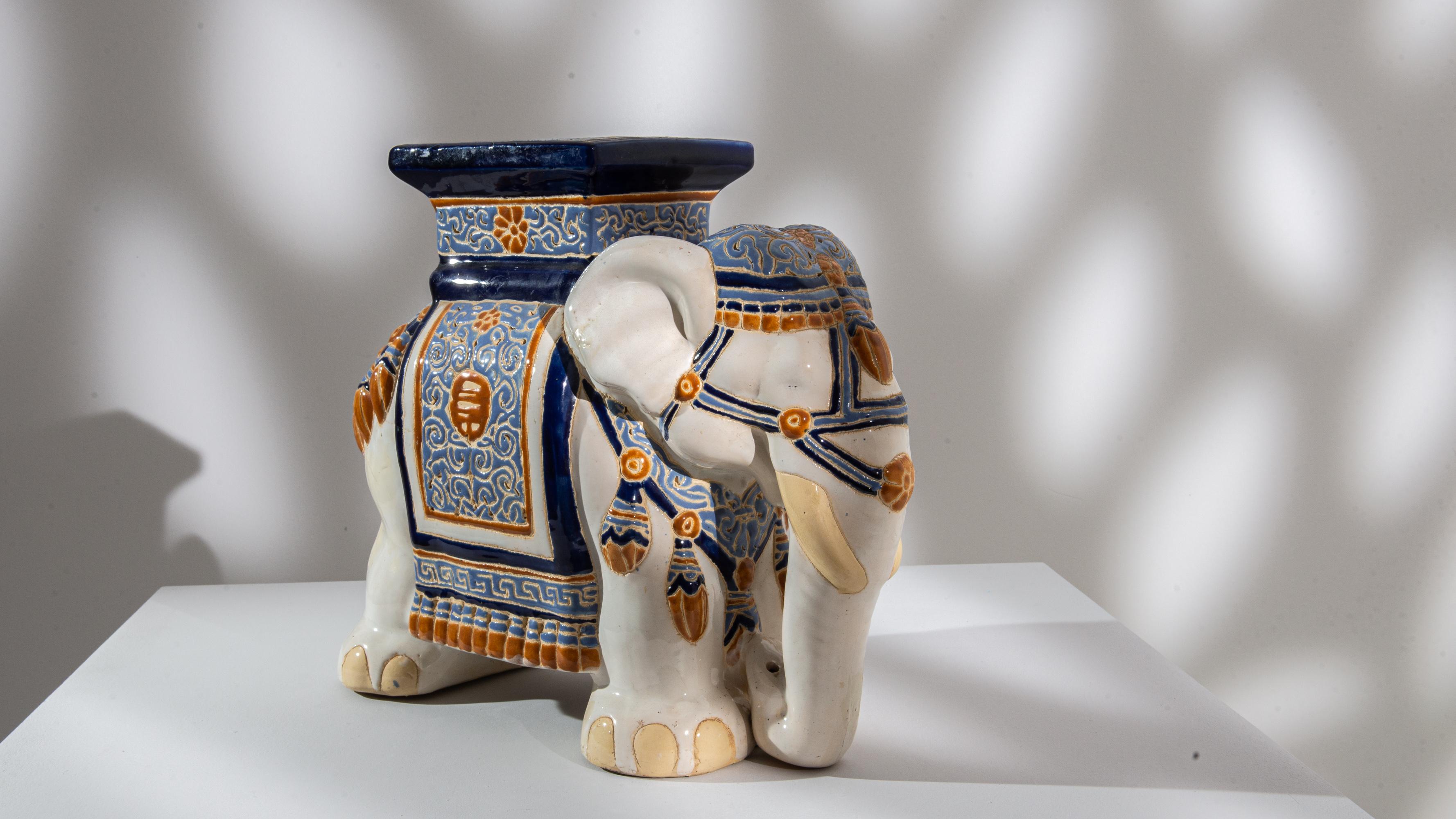 A ceramic decoration from 1960s France in the shape of an elephant. Glazed in bright white laced with powder blue and yellow ochre; the saddle, seat and blanket are delicately patterned — reflecting Chinese and Arabic influences — suggestinging the