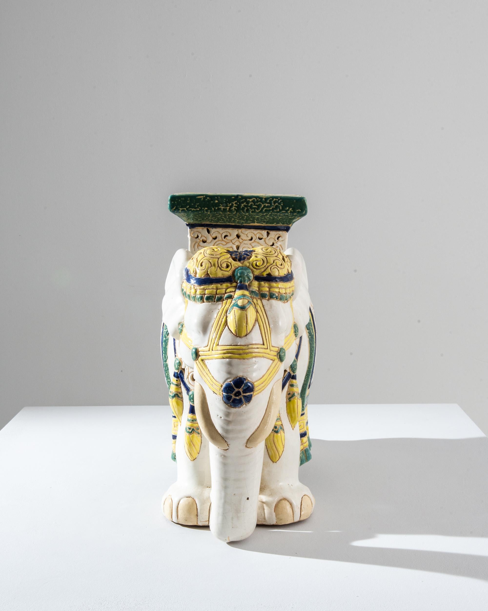 A ceramic decoration from 1960s France in the shape of an elephant. Glazed in bright white laced with powder blue and sunny yellow; the saddle, seat and blanket are delicately patterned — reflecting Chinese and Arabic influences — suggesting the