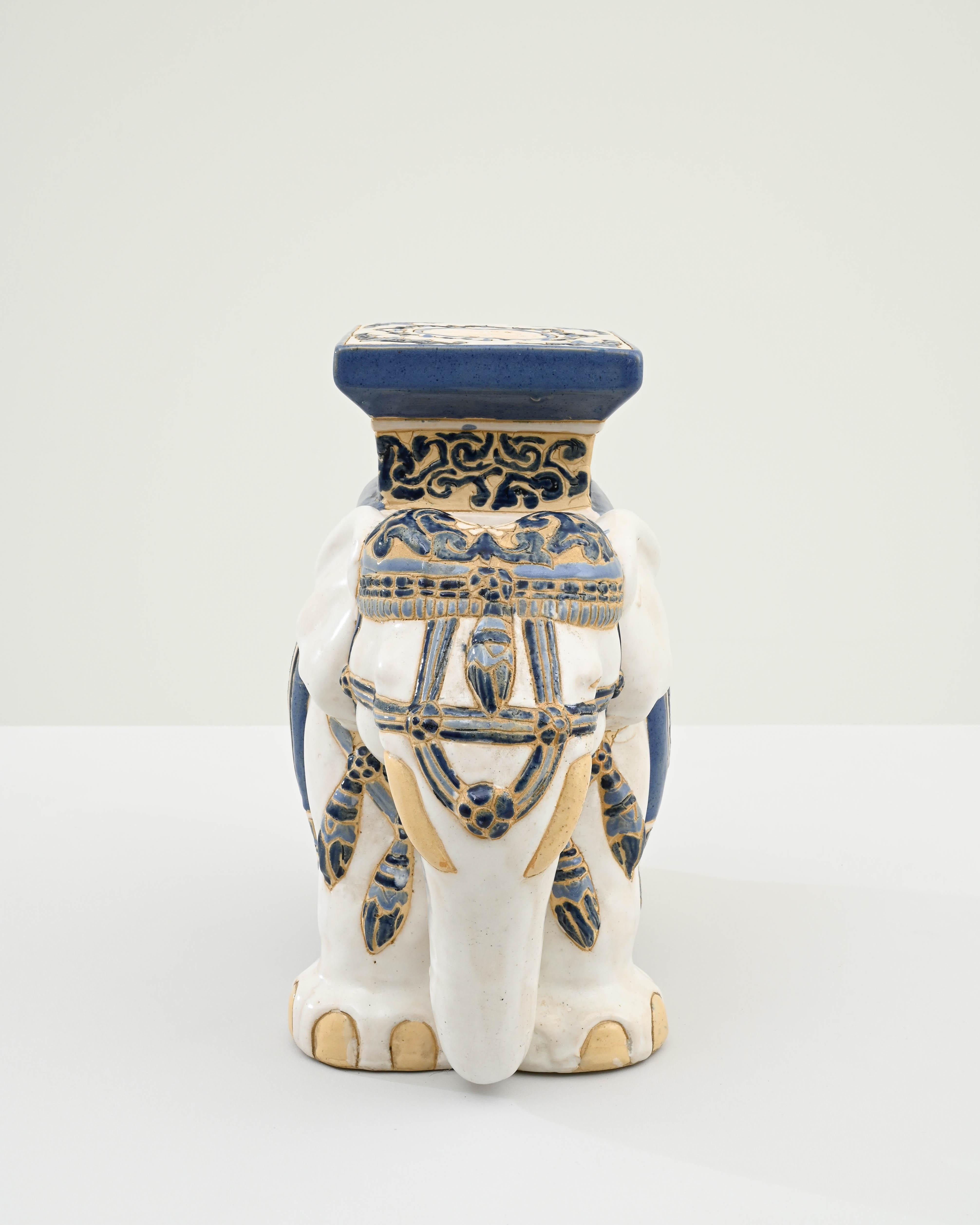 A ceramic decoration from 1960s France in the shape of an elephant. A saddle seat and blanket are glazed with indigo blue, the elephant’s skin painted with glossy white and laced with lines of the earth tone clay body; the assortment of delicate
