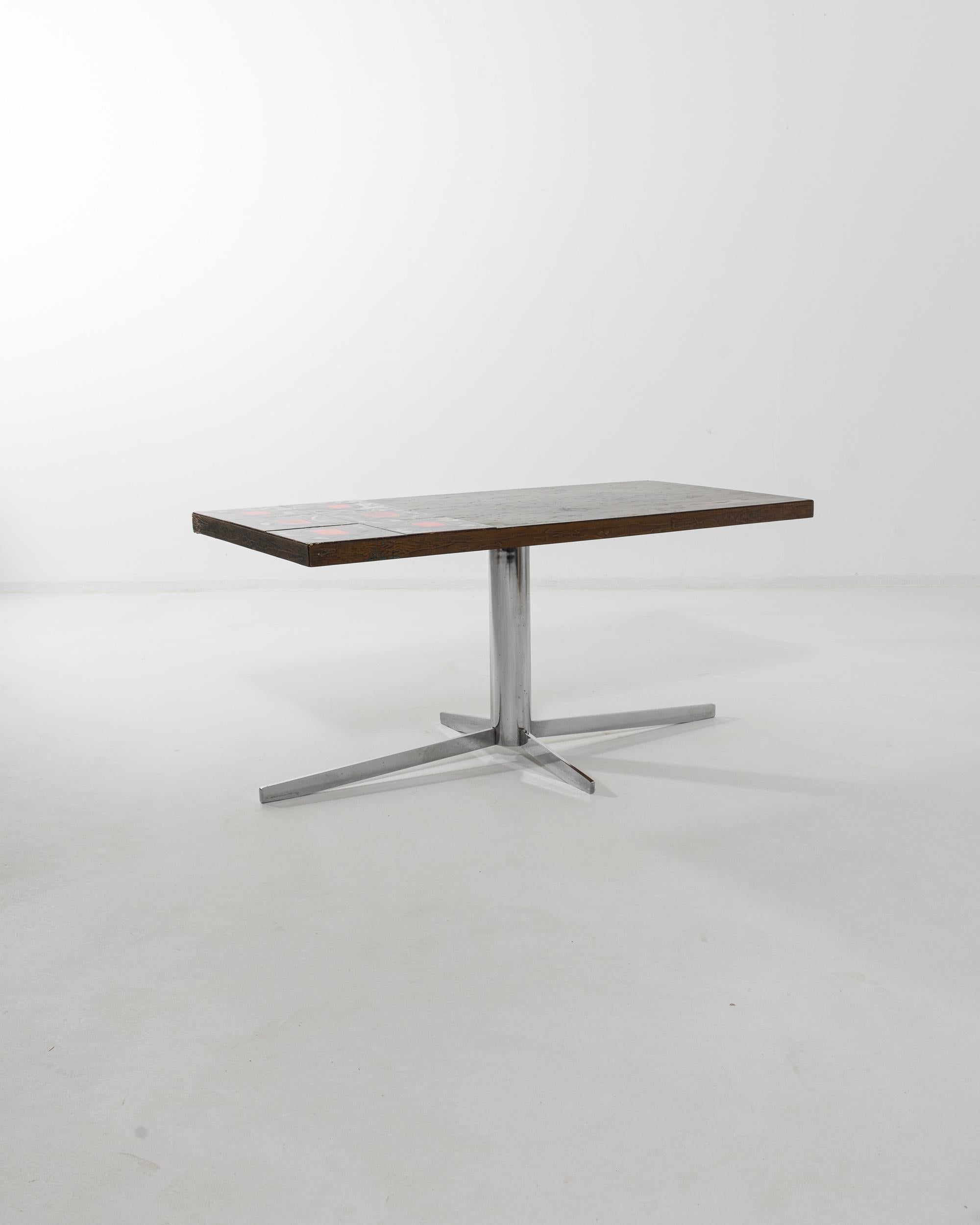 Made in 20th century France, this vintage coffee table epitomizes the bold, idiosyncratic designs of the 1960s. A simple rectangular tabletop rests upon a streamlined base of polished silver steel —but the sleek minimalism of the silhouette is