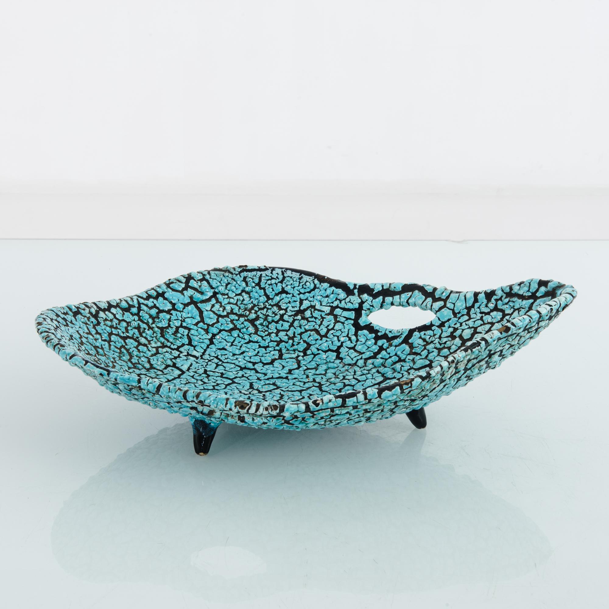 Made in France, circa 1960, this ceramic tray features a turquoise mosaic against a sea of black. Slightly elevated on feet, the tray displays a rounded form, which is curved along the edges. An eye-shaped opening adds a touch of intrigue to this
