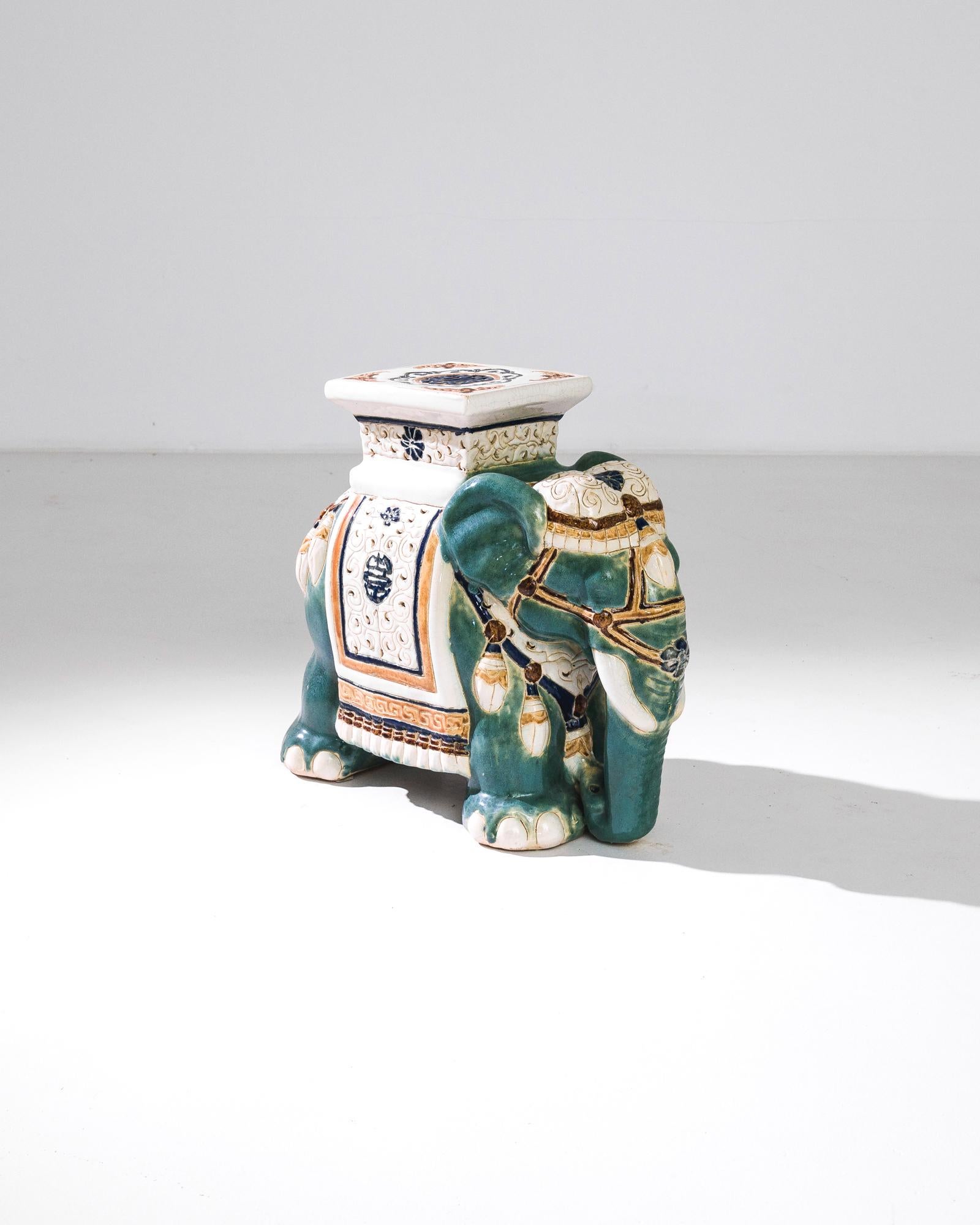 A ceramic decoration from 1960s France in the shape of an elephant. A saddle seat and blanket are glazed in whites, greens and earth tones; the assortment of delicate patterns — reflecting Chinese and Arabic influences — suggest the romance of the