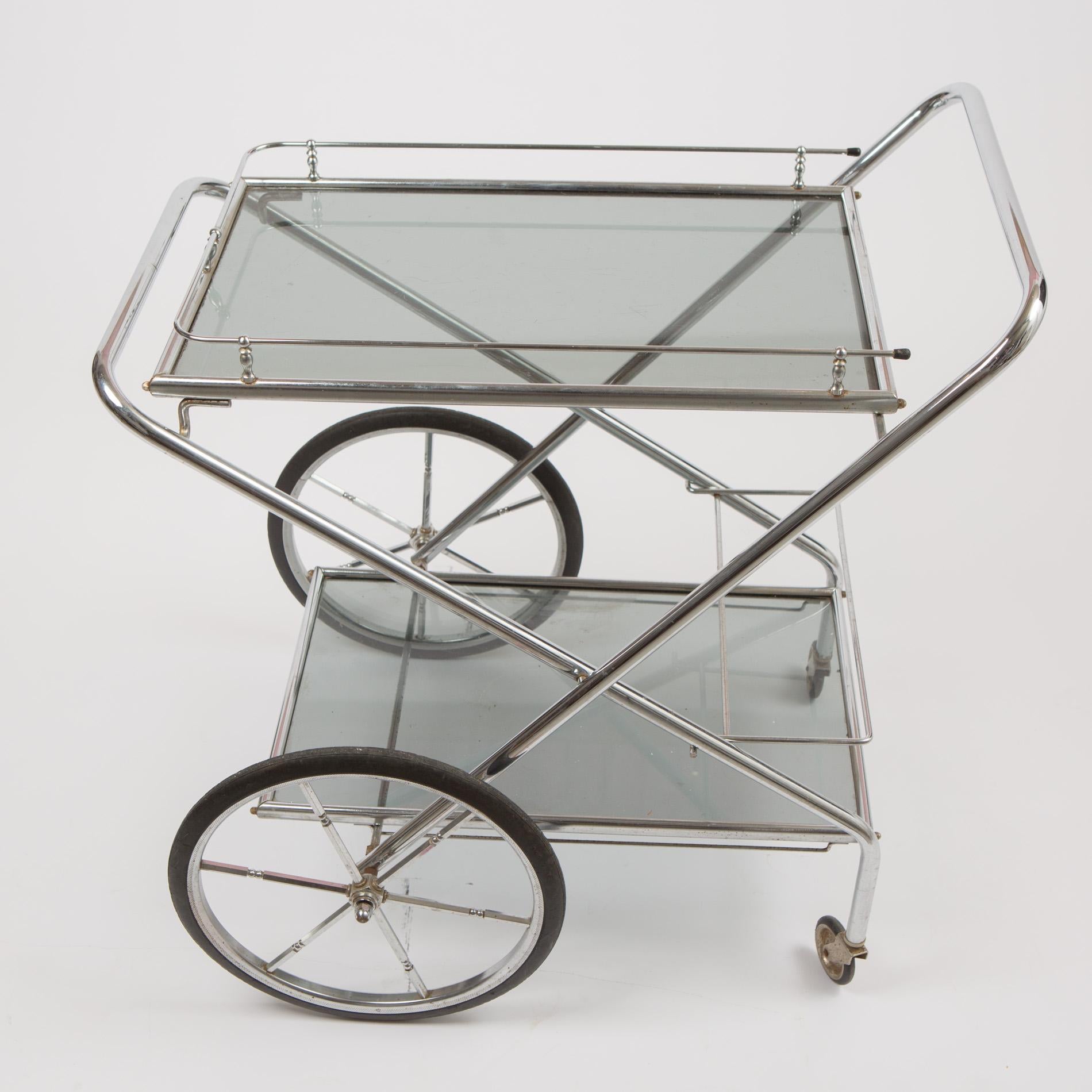 Chic chrome drinks trolley with two Smokey glass shelves and oversized wheels. Tubular frame supports both shelves and creates a handle to one side. The top shelf is surrounded by a decorative curved chrome frame, the bottom shelf features a bottle