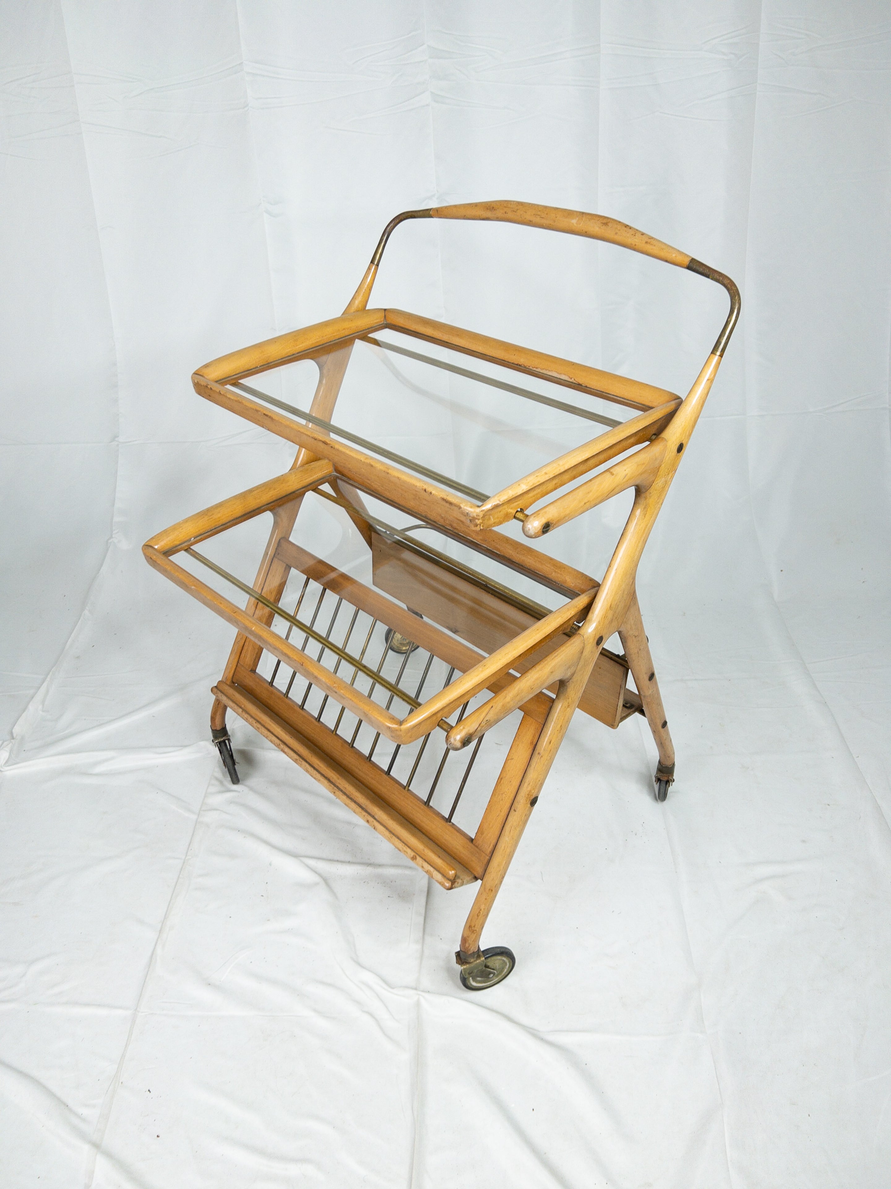 The 1960s French collapsible wooden bar cart encapsulates the essence of mid-century modern design with its sleek and functional aesthetic. Crafted from rich, warm wood, this exquisite piece seamlessly merges form and function. Its ingeniously