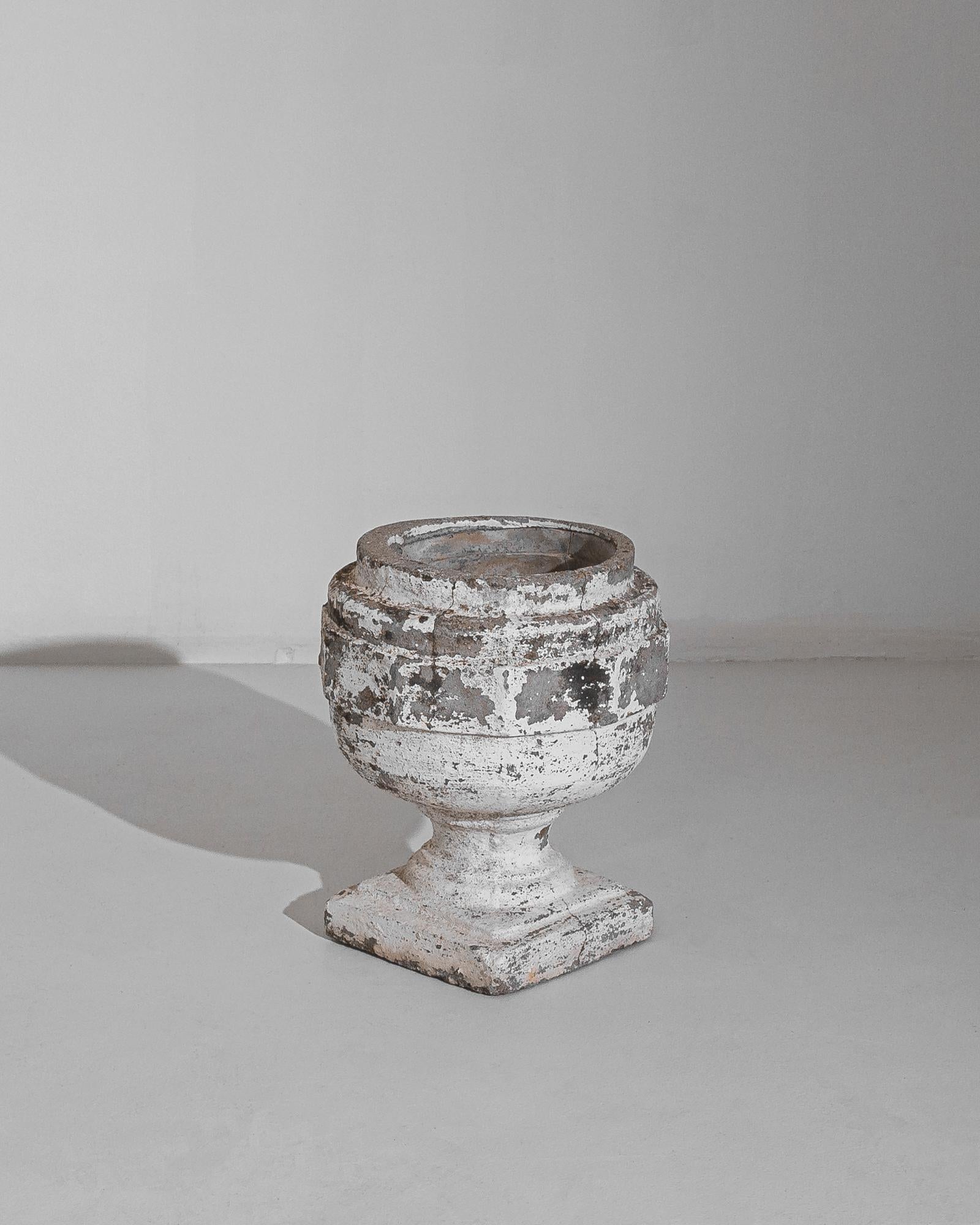 This concrete planter was made in France, circa 1960. The full rounded body recalls a goblet resting on a stepped square plinth. Beautifully weathered with vestiges of white paint on its gravelly surface, this planter will be a choice display piece