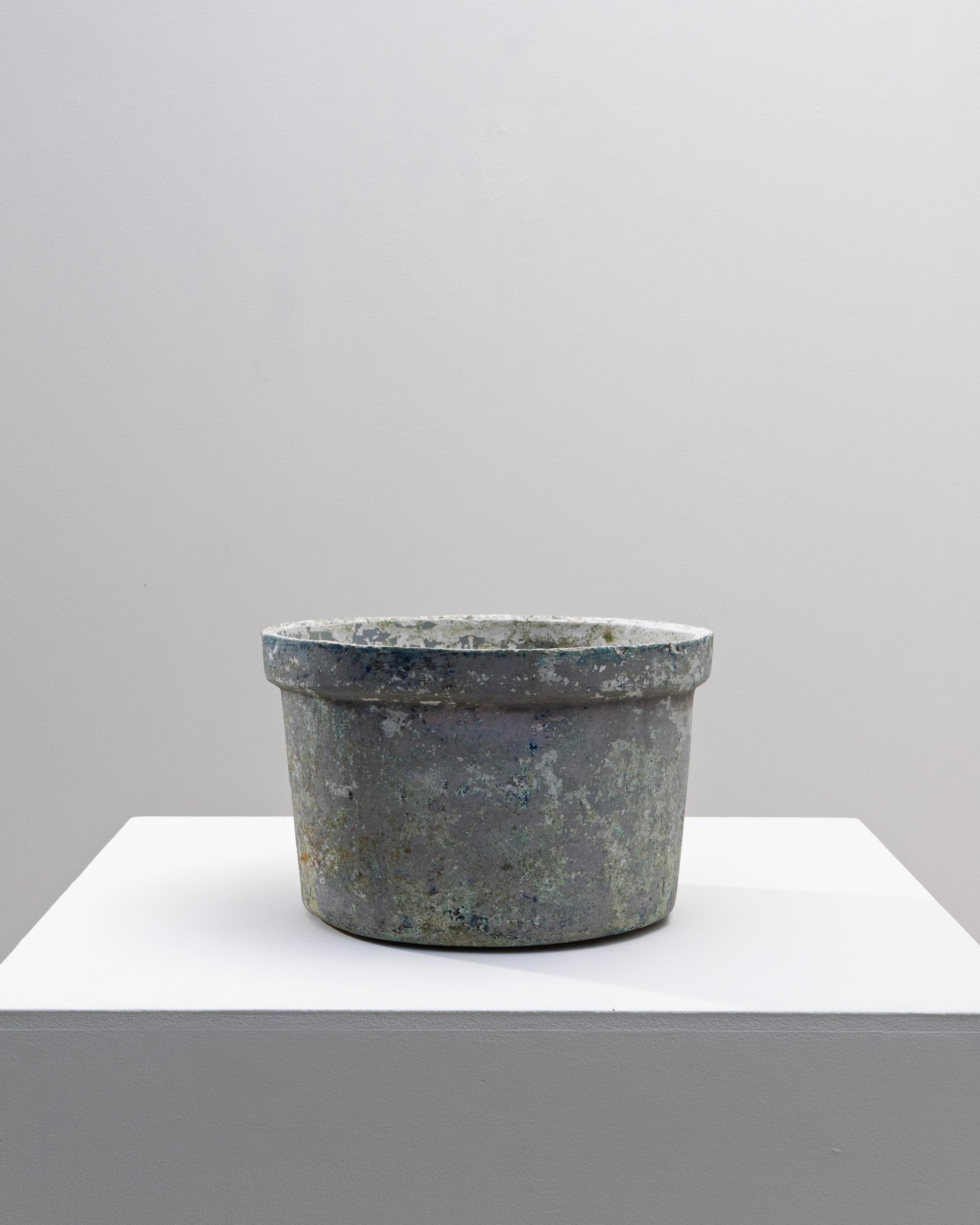 This 1960s French concrete planter showcases the understated beauty of utilitarian design, enriched by decades of natural weathering. Its cylindrical form is thick-walled and weighty, offering durability suited for both indoor and outdoor settings.