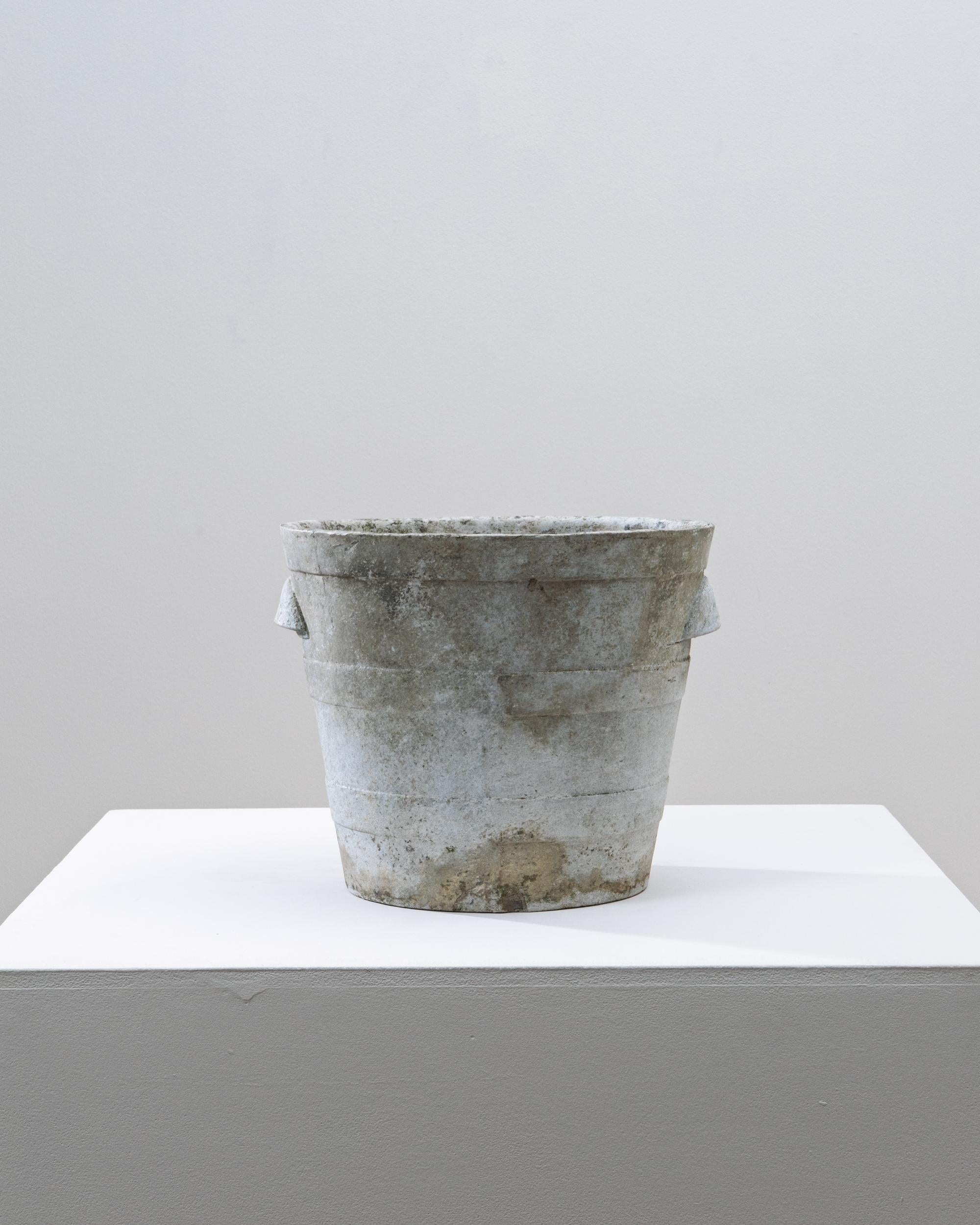 1960s French Concrete Planter. This mid-century French concrete planter features a tapered cylindrical form with subtle horizontal banding and small side handles that enhance its practical, utilitarian charm. The surface is richly weathered,