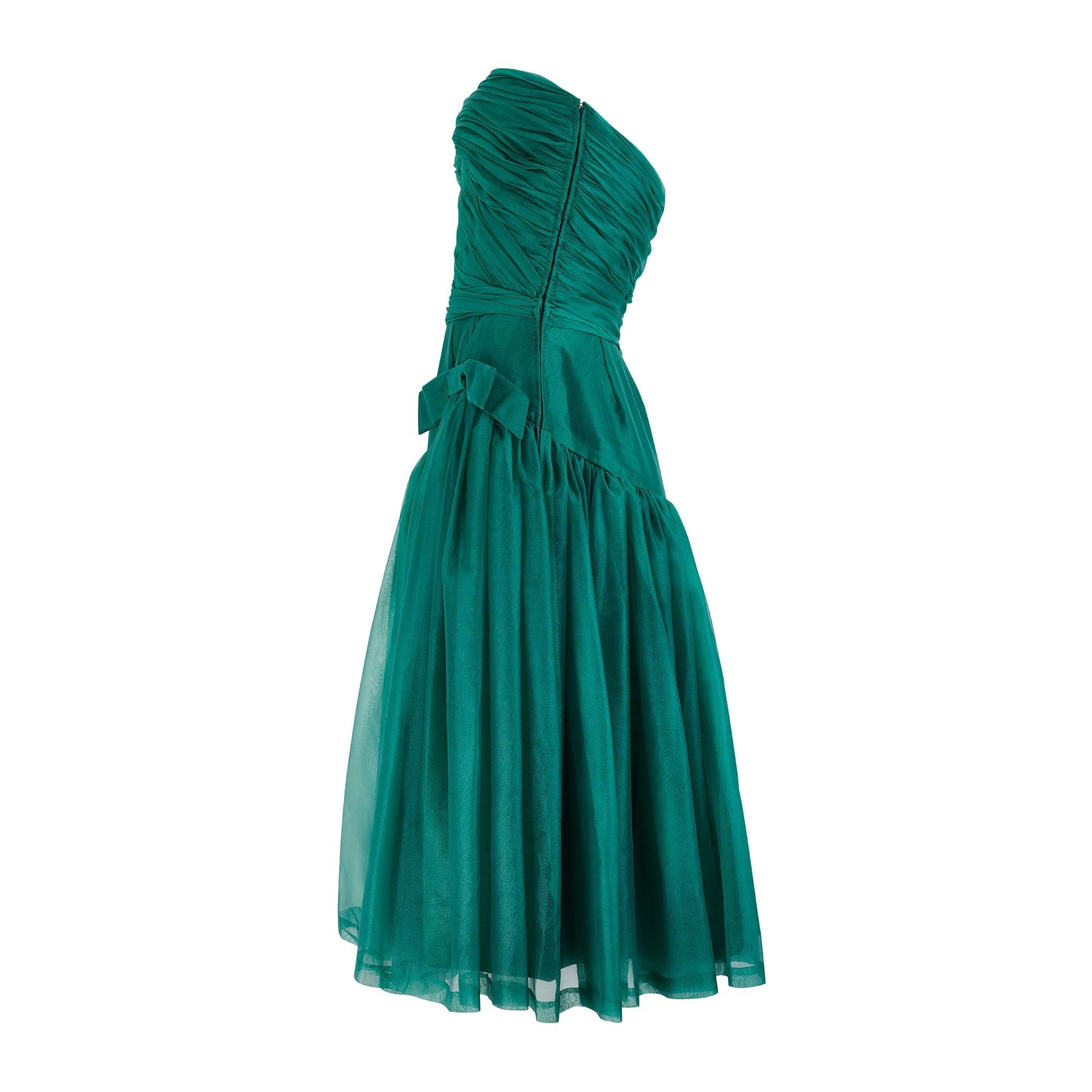 This sensational early 1960s emerald green chiffon dress is of superb quality and has absolutely beautiful construction. Made in France and probably from a smaller Parisian couturier, the sheer chiffon overlay is delicately ruched over the