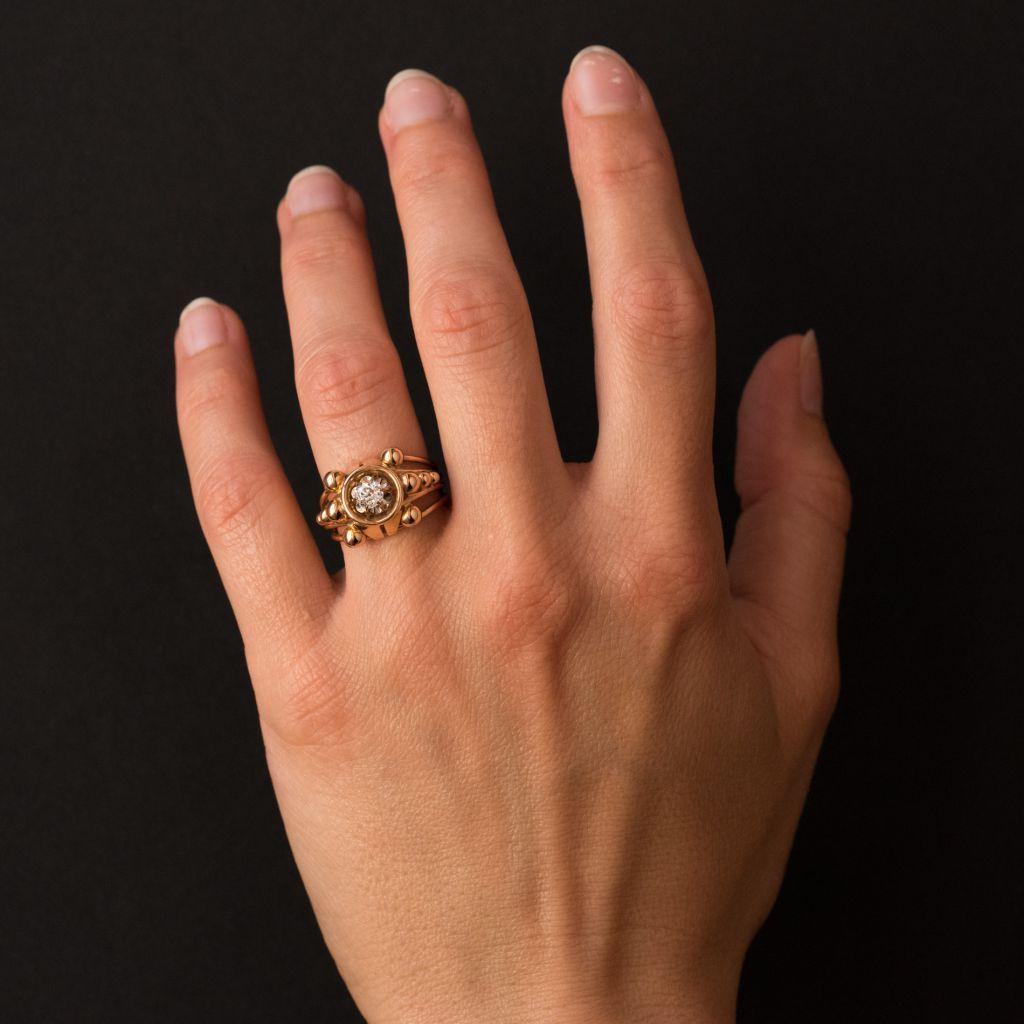 Ring in 18 karat yellow gold, eagle head hallmark. 
This ring features a central brilliant- cut diamond set with 6 claws in an openwork mounting. On each side are 5 round golden pearls. The ring band is formed of 4 golden strands that join at the