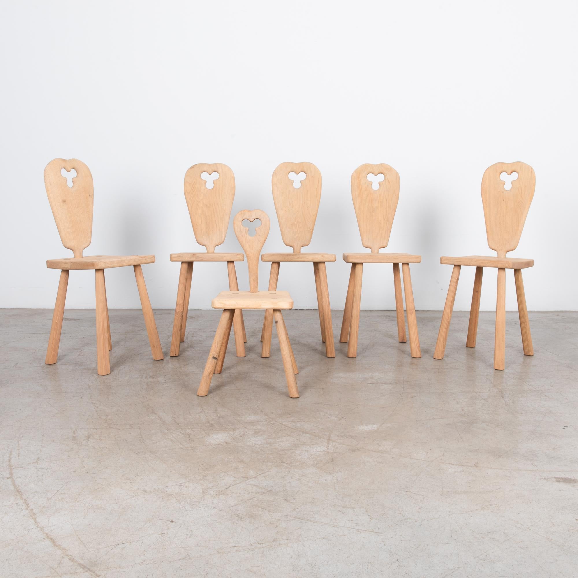 A minimal design in European oak, circa 1960. This unique set of dining chairs features one miniature version, great addition to complete the ensemble. The paired down design uses minimal parts, with one small ornament, a triangular shaped hole on